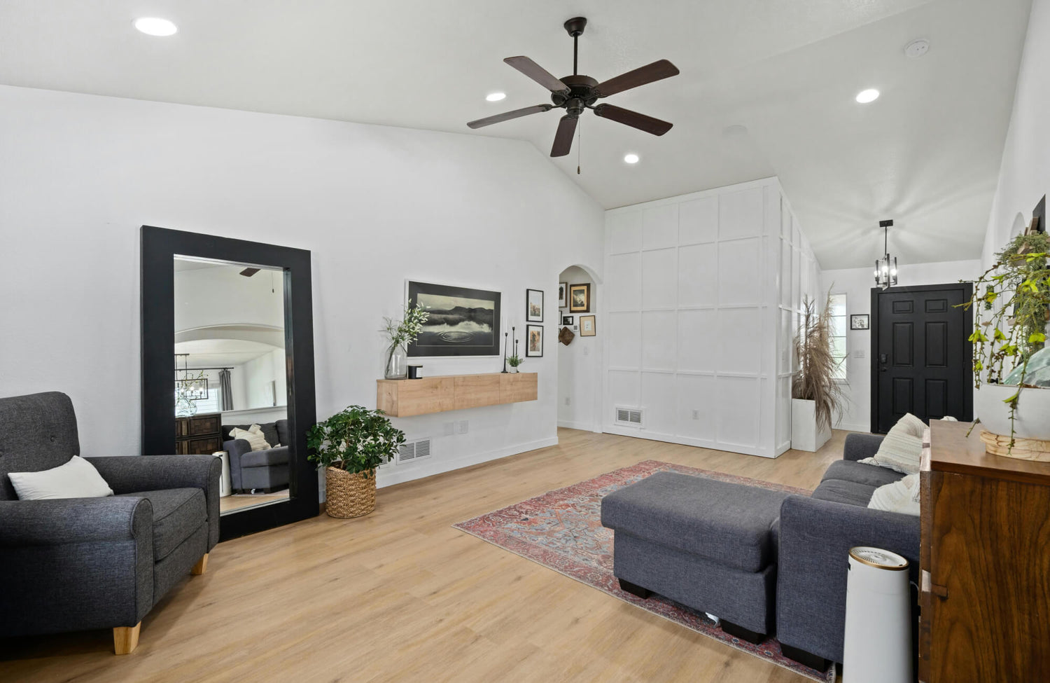 Large floor mirror leaning against the wall beside an armchair in a bright, open living room.