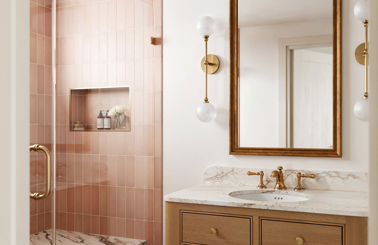 Soft vertical sconces beside the mirror illuminate the vanity, creating balanced light across the marble surface.