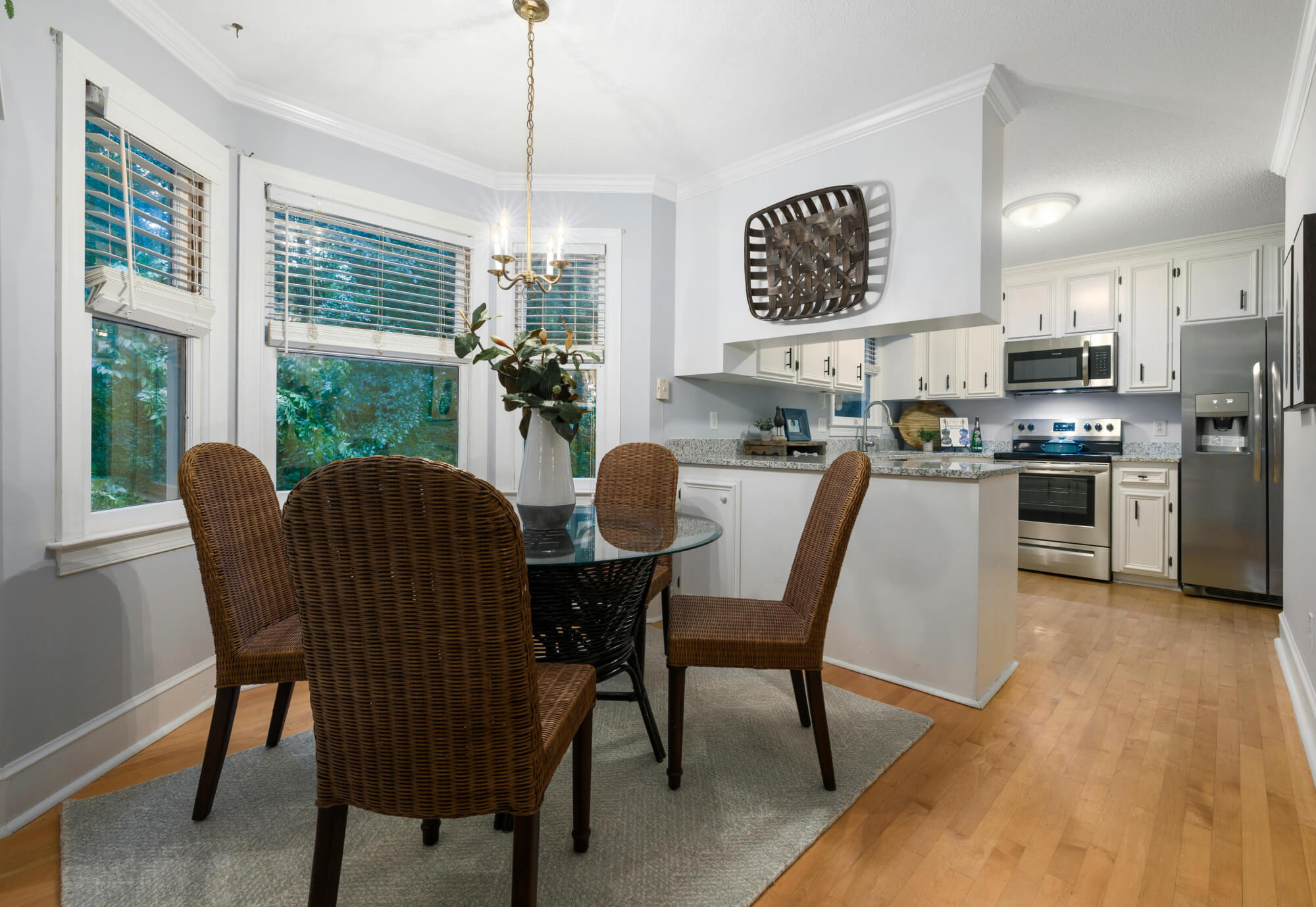 Dining rug centered under a round table, extending beyond chairs to define a compact dining area near the kitchen