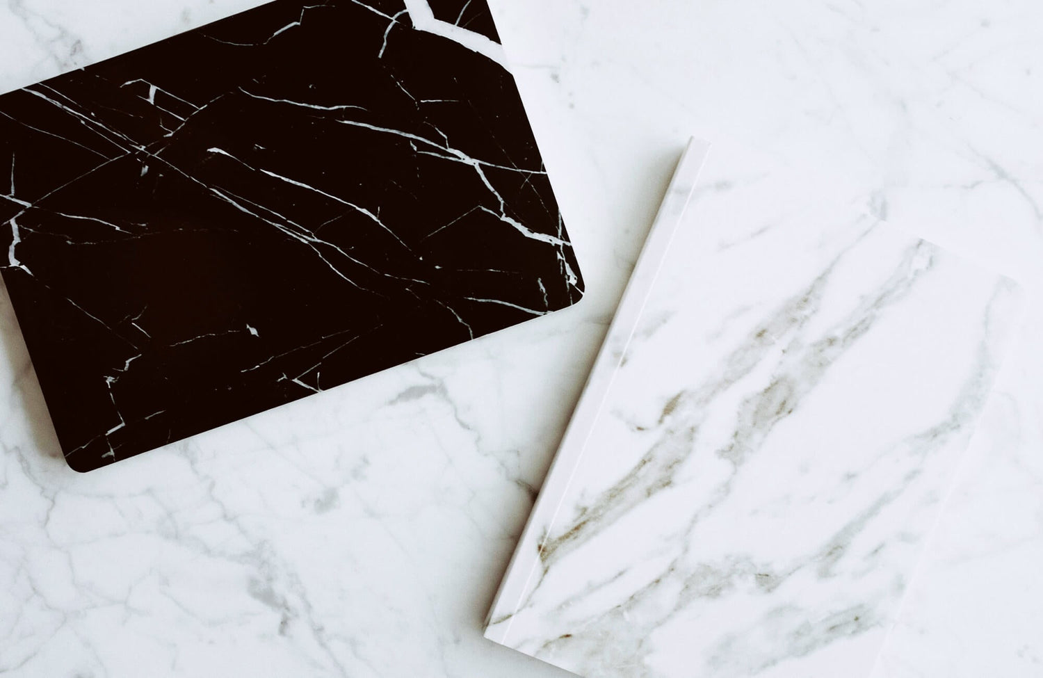 White marble look tile with light gray veining beside a rich dark brown marble piece, showing how color variation and veining create a natural stone appearance.