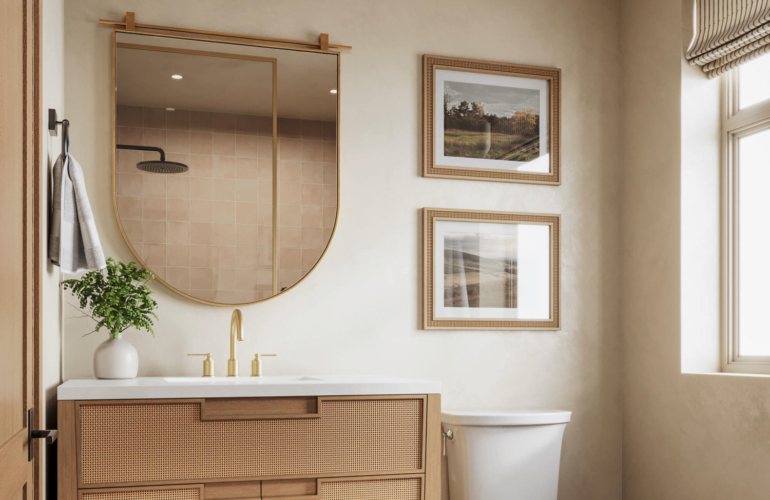 Rounded rectangular mirror with gold frame above a cane-front vanity and brushed gold faucet, styled in a warm, neutral bathroom with natural light.