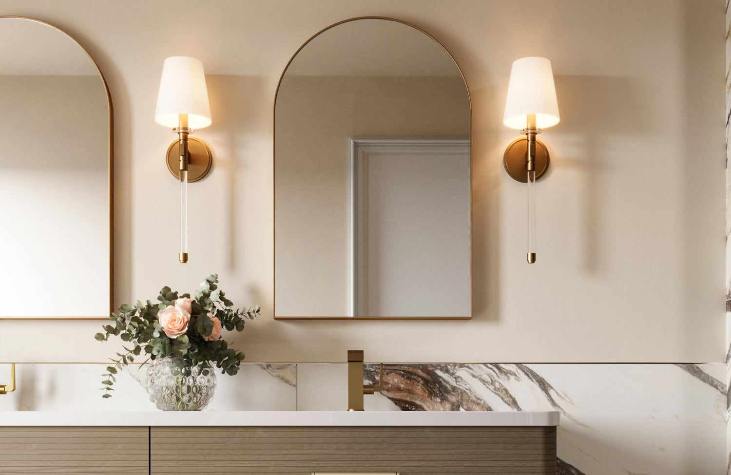 A pair of arched mirrors with elegant brass-framed sconces brings timeless symmetry and warmth to this refined bathroom vanity setup