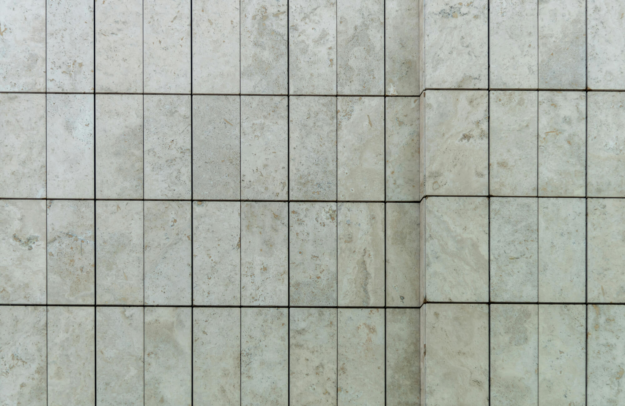 Close-up of stone subway tile wall with visible horizontal crack line across multiple tiles and dark grout joints.