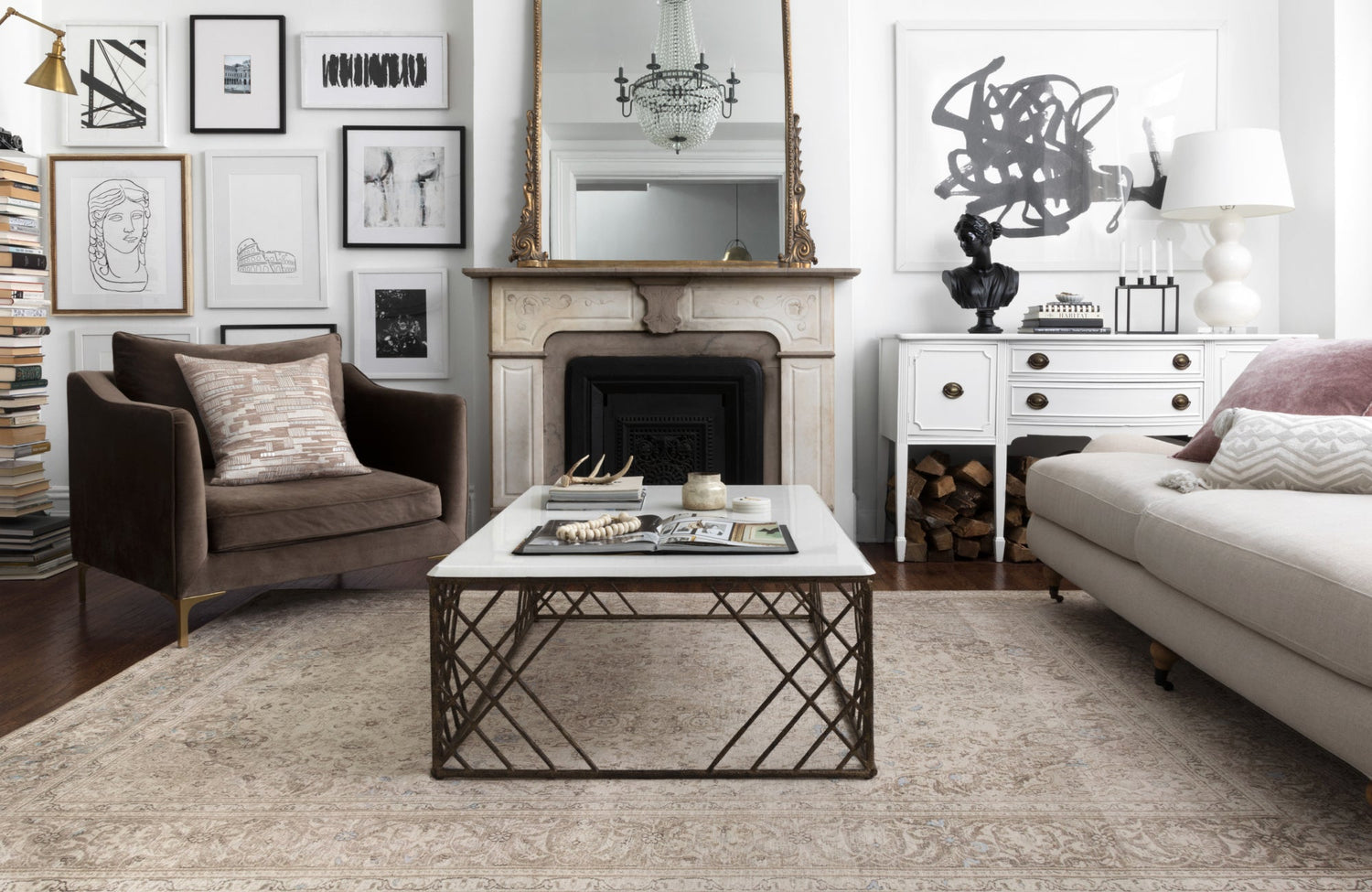 Elegant living room with a vintage-style rug and classic décor, featuring a gallery wall and marble fireplace.