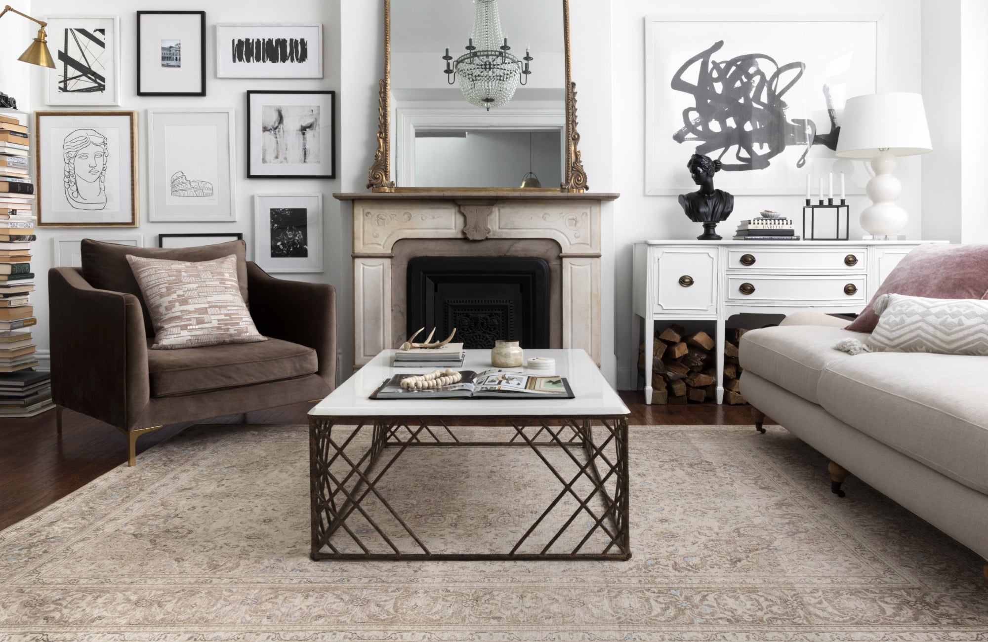 Elegant living room with a vintage-style rug and classic décor, featuring a gallery wall and marble fireplace.