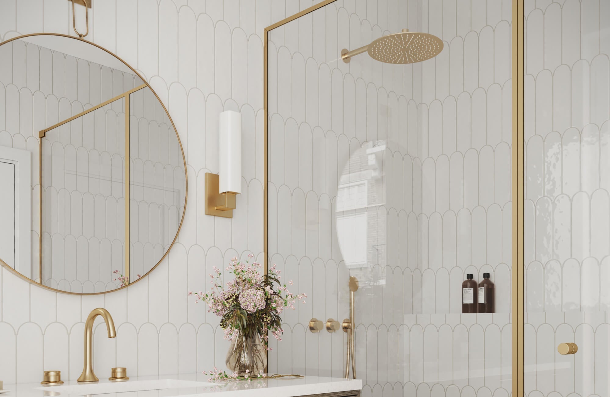 Elegant bathroom with white scalloped wall tiles, accented by brushed gold fixtures, a round mirror, and vertical sconces.