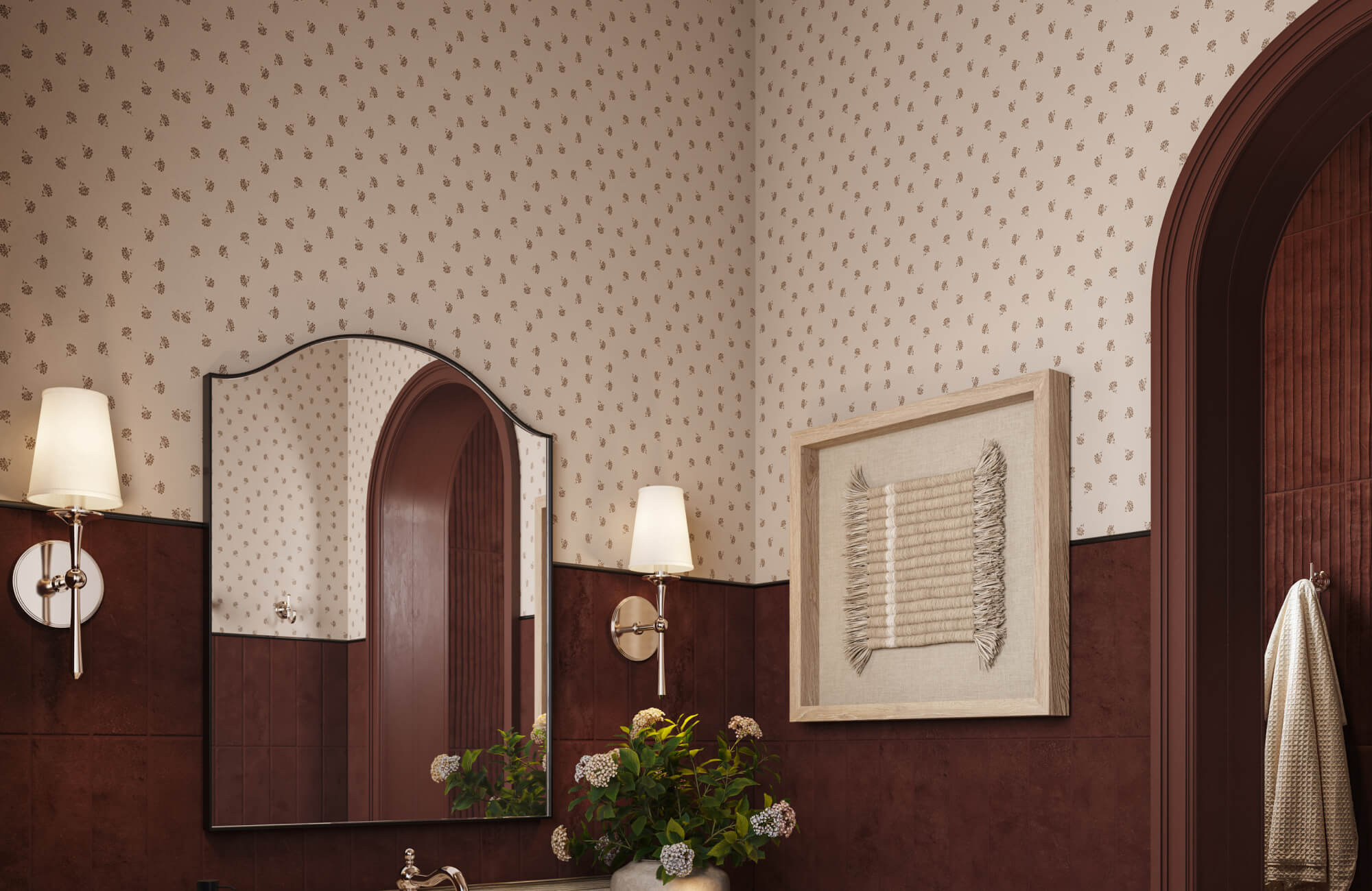 Vintage-inspired bathroom with reddish brown subway tile wall, delicate patterned wallpaper, wall art, and an arched mirror with brass sconces.