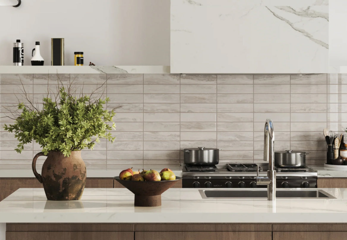 Elegant kitchen countertop with various cooking utensils and ingredients, backed by sleek, marble look beige tiles, creating a modern and clean aesthetic