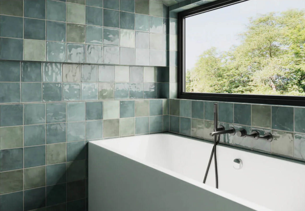 Soothing bathroom with serene green tiles in a subtle gloss finish, black modern faucet, and a window view of nature