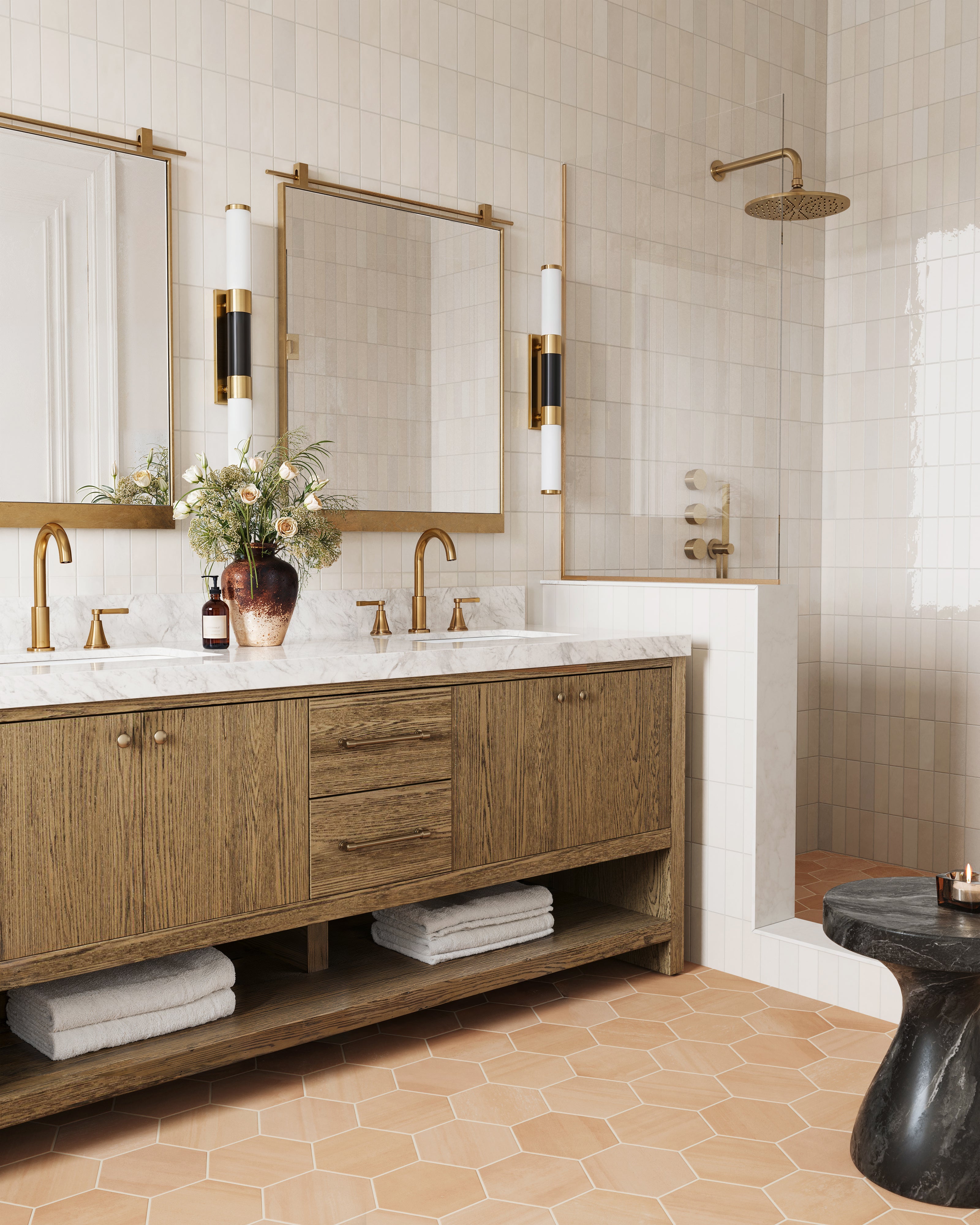 Light-filled bathroom with brass accents and wood vanity featuring Jojo 2x6.3 glossy ceramic tile in Ivory, adding soft off-white warmth and gentle texture to the shower wall.