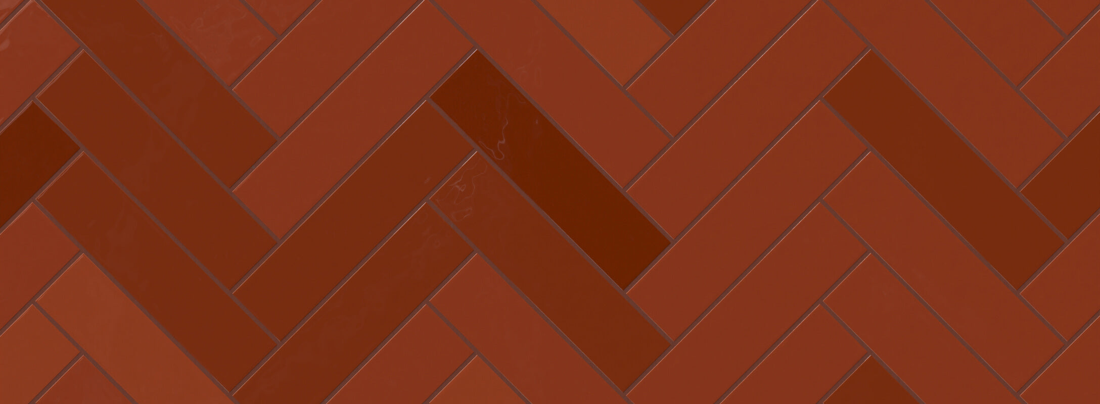Bold red herringbone tiles with a glossy finish, creating a striking and dynamic pattern ideal for walls or backsplashes