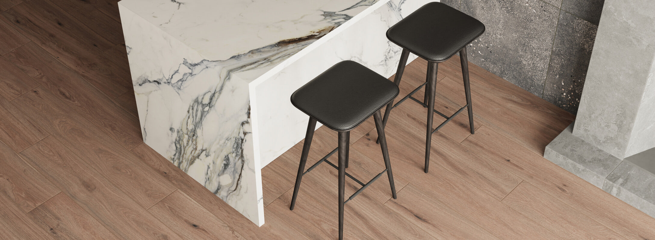 Wood-look kitchen floor tiles paired with a marble island, two black bar stools, and a textured stone backdrop