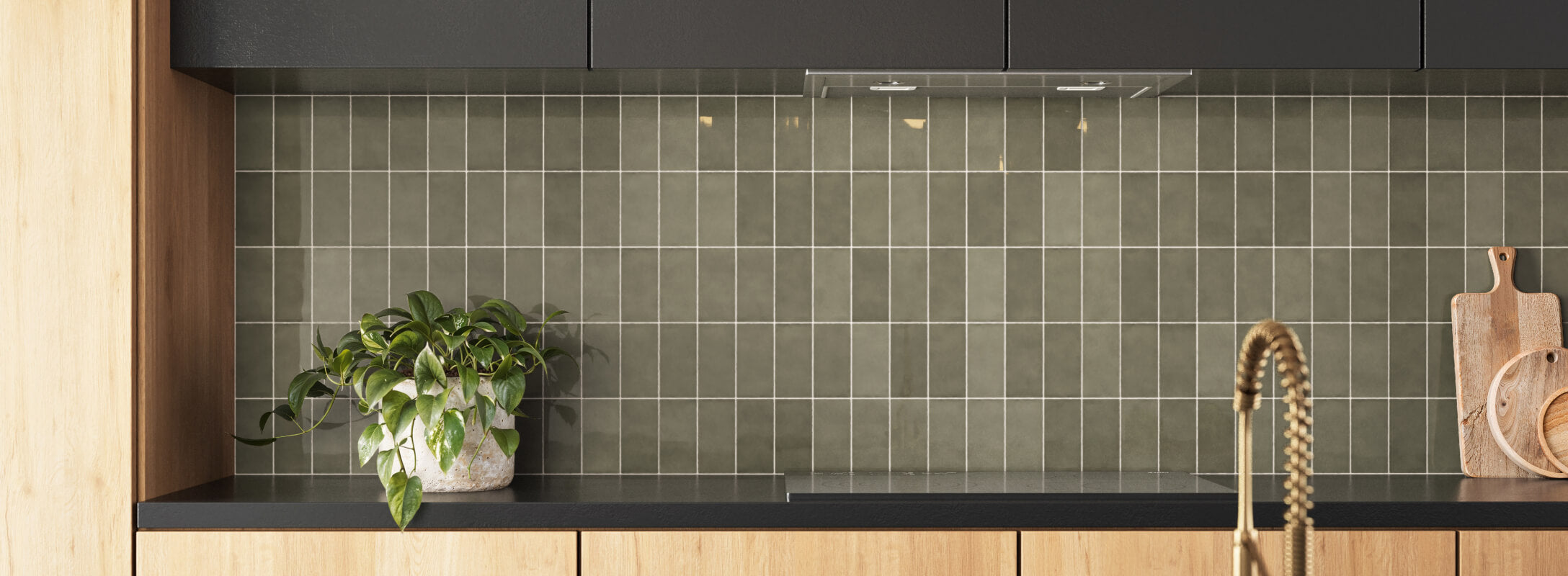Modern kitchen backsplash with olive green subway tiles, complemented by wooden cabinets and a black countertop, featuring a potted plant and wooden cutting boards