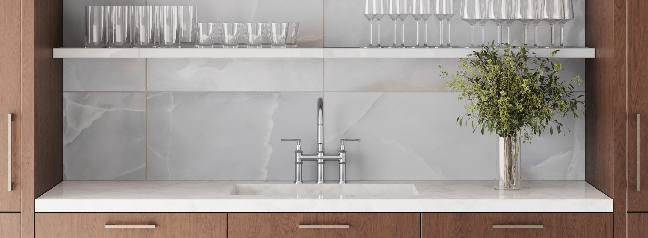 Modern kitchen backsplash with large light grey tiles, white shelving with glassware, and a sleek silver faucet set against warm wooden cabinets