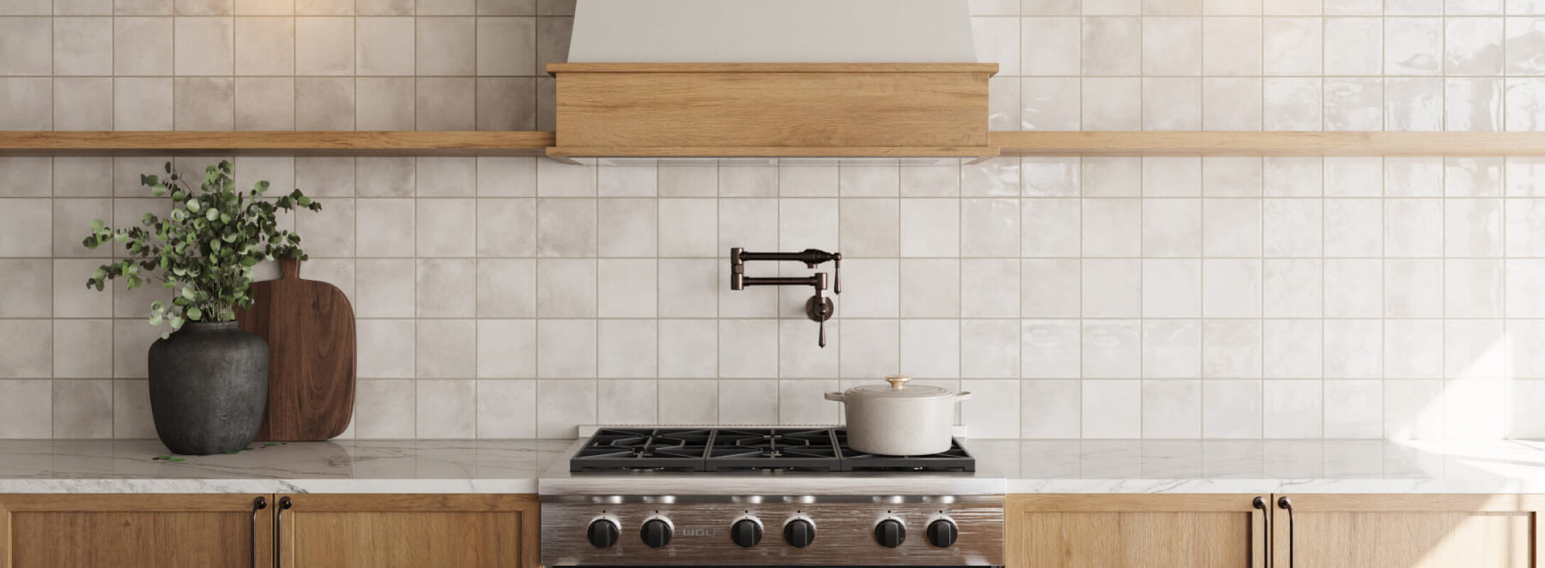 Glossy taupe kitchen tiles create an elegant backsplash, accented by a wooden range hood and modern stainless steel stove