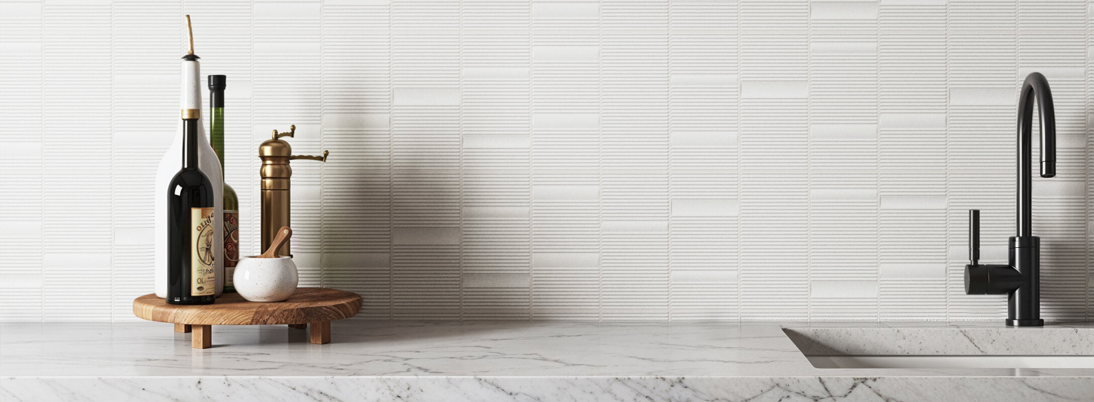 White textured tiles forming a sleek backsplash, complemented by a black faucet and a wooden tray with olive oil bottles