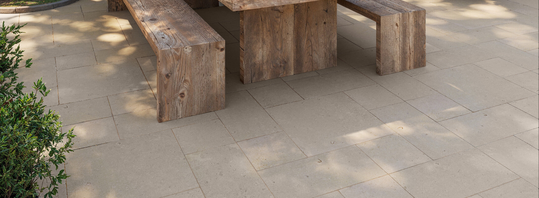 Beige paver tiles with a smooth, natural finish complement rustic wooden benches, creating a serene and inviting outdoor space.