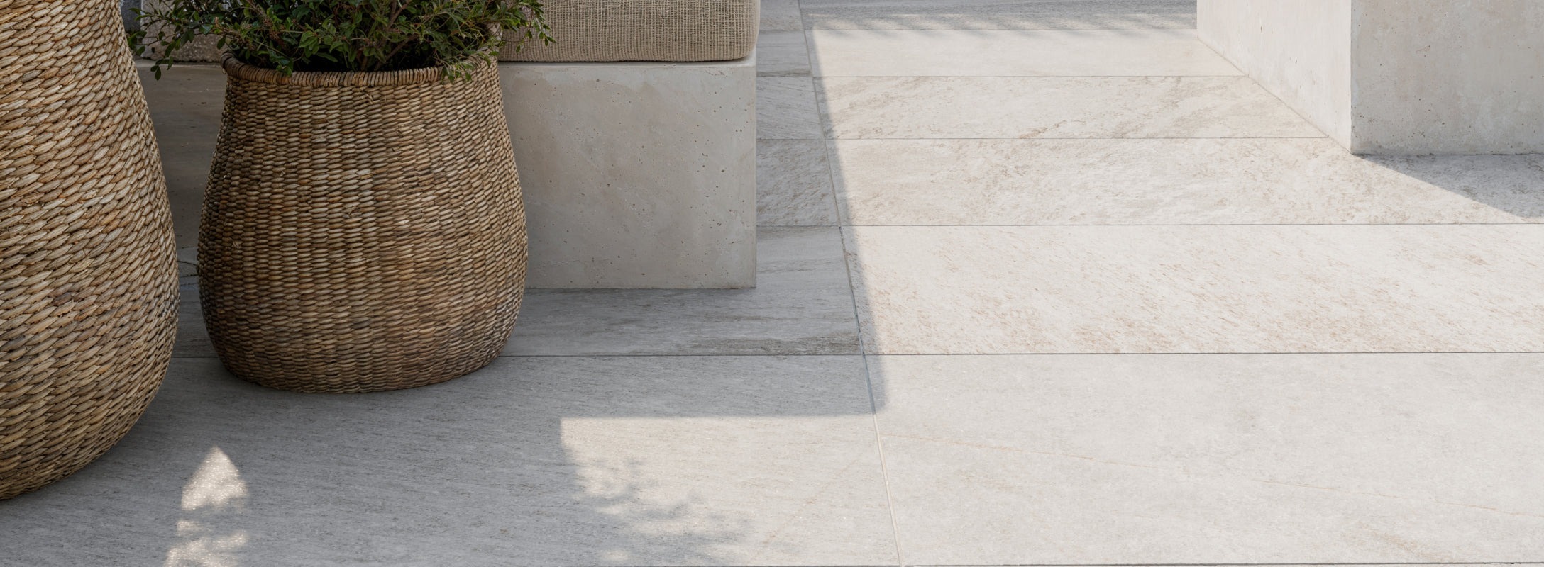 Light beige paver tiles with a natural stone texture create a serene outdoor space, paired with woven baskets and minimalist seating.
