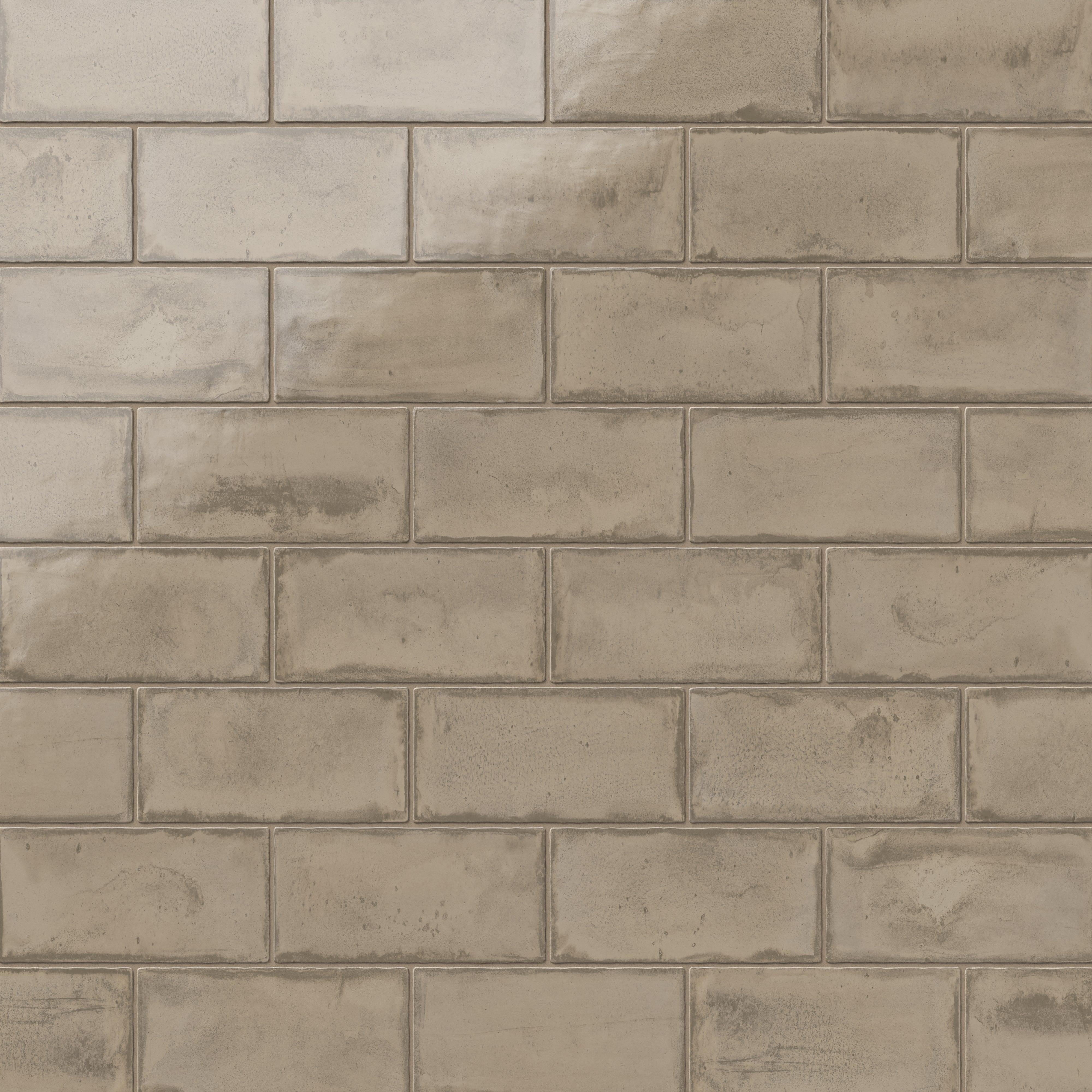 Glossy taupe ceramic subway tiles in a 3x6 format and subtle handcrafted texture, perfect for creating a natural, warm ambiance