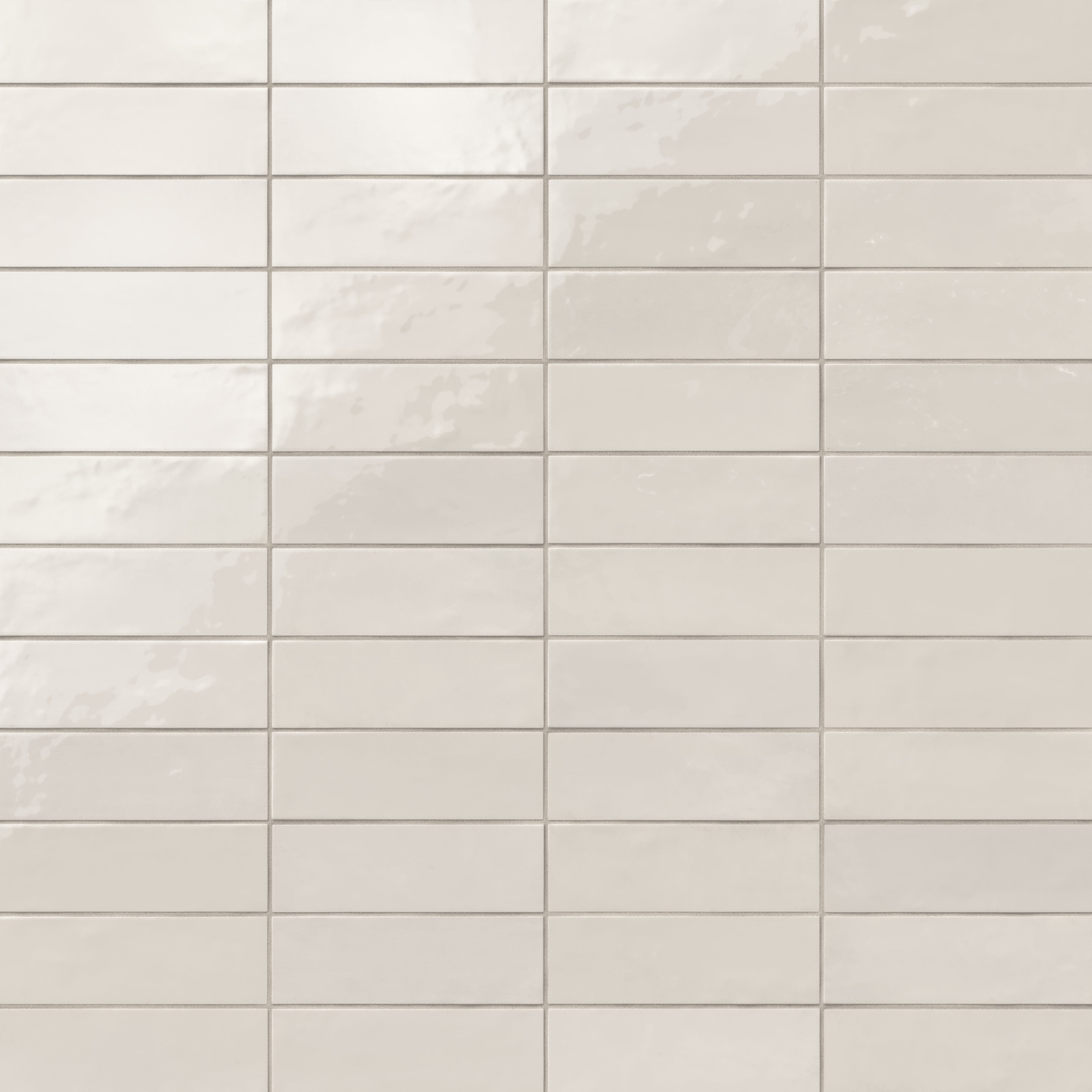 Glossy subway tiles in shifting white tones with an artisan-like surface and subtle reflective finish.