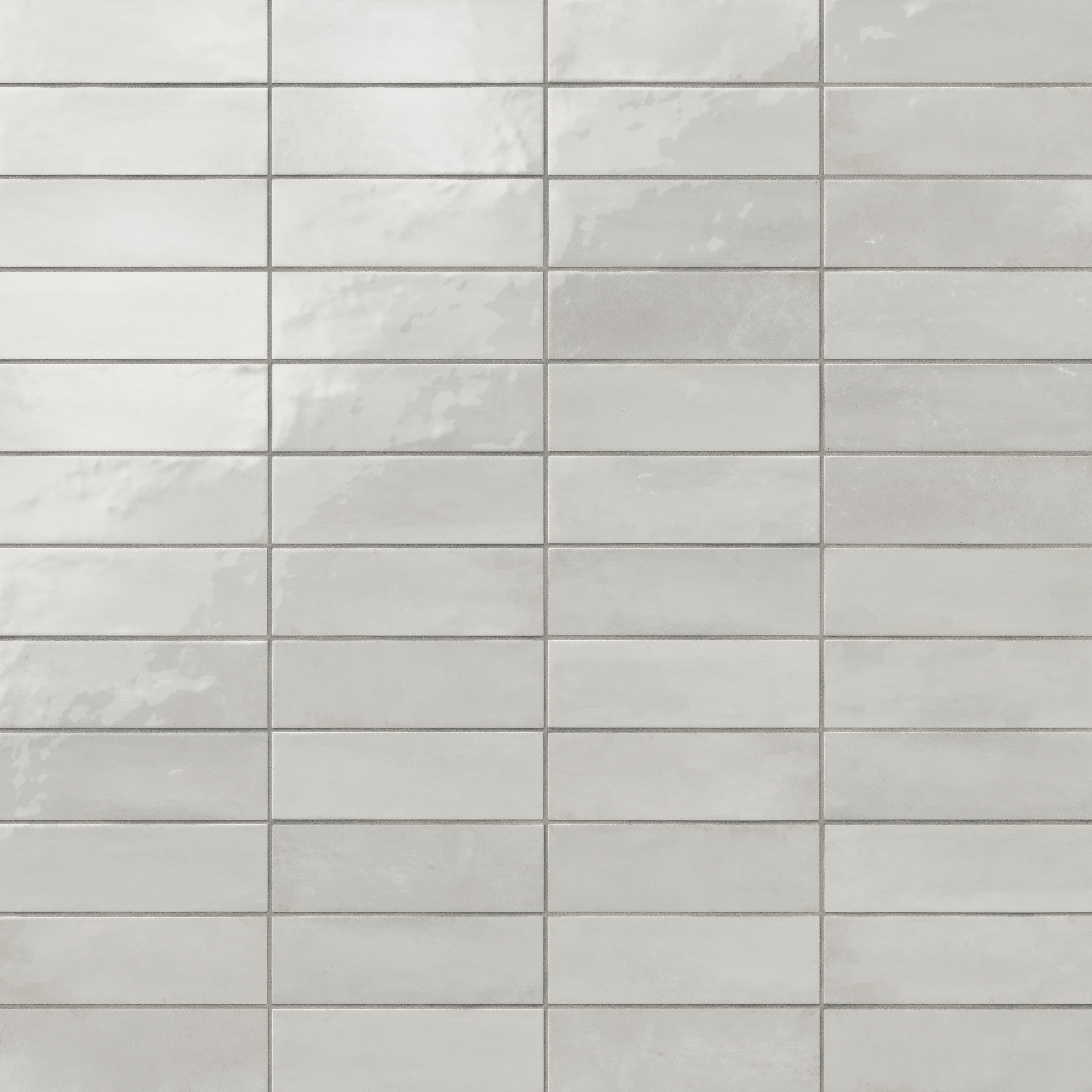 Glossy subway tiles in shifting light gray tones with an artisan-like surface and subtle reflective finish
