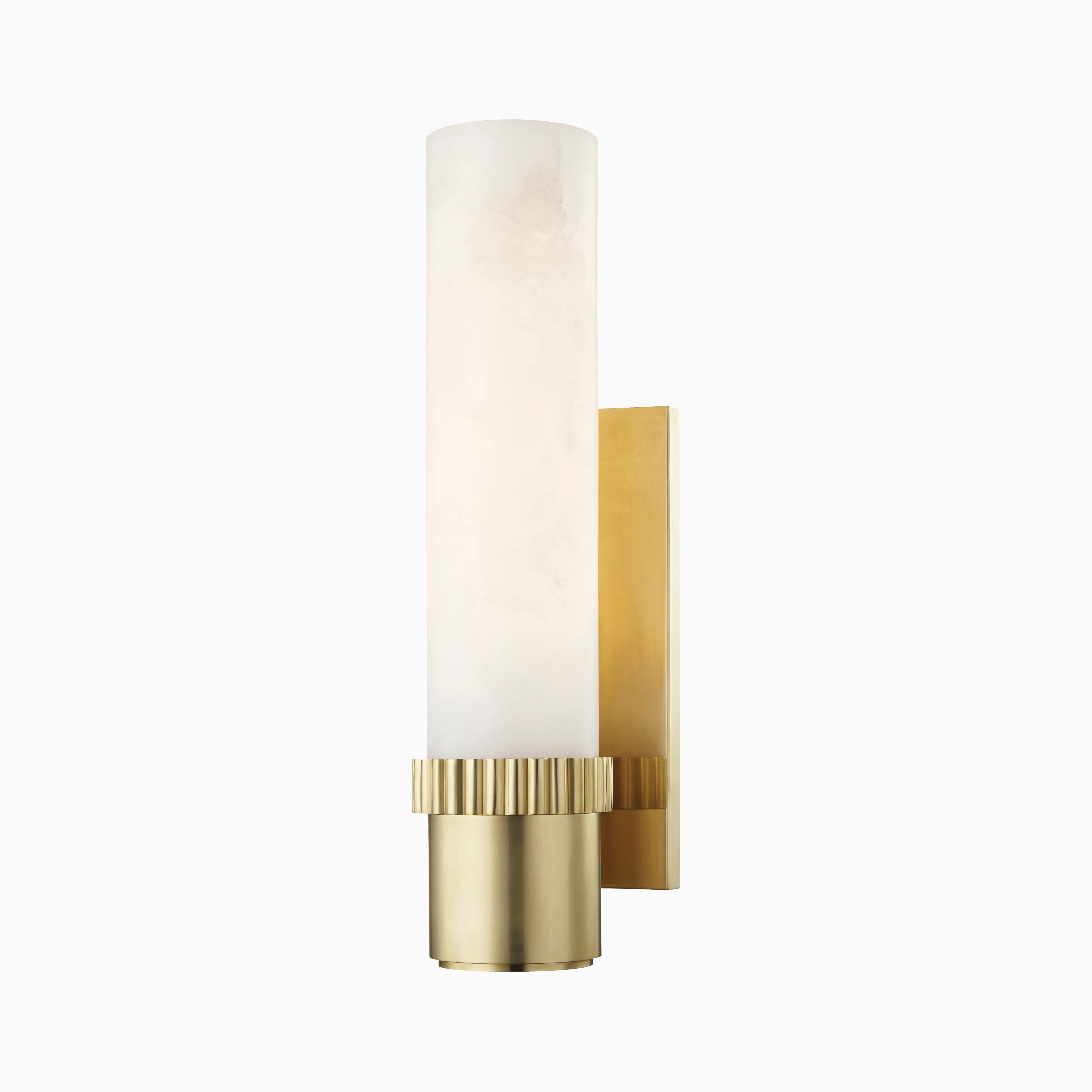Asha wall sconce in aged brass with a fluted cylindrical base and alabaster shade, delivering timeless glow with modern refinement