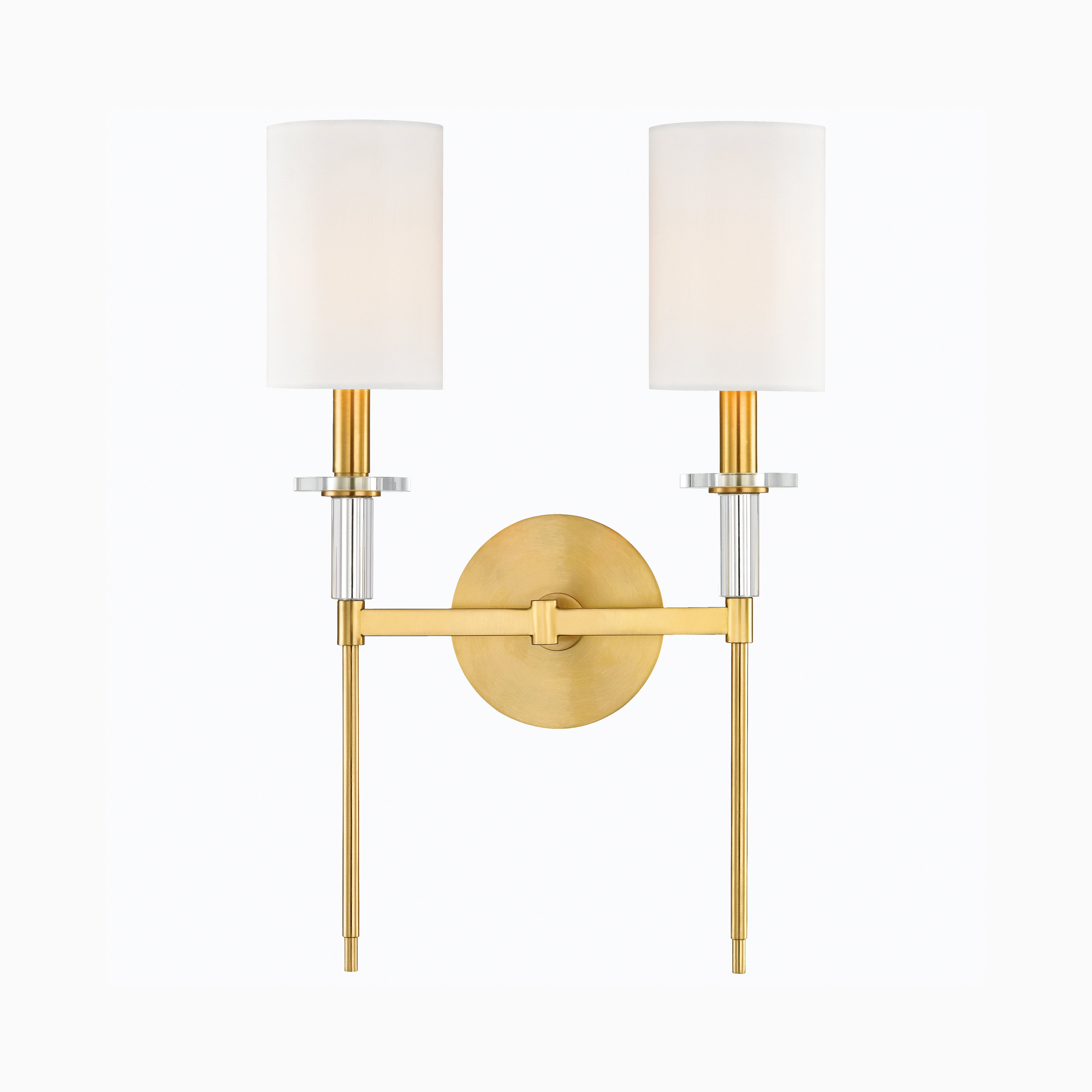 Refined double sconce in aged brass with twin white natural fabric shades and fluted brass accents, perfect for balanced elegance.