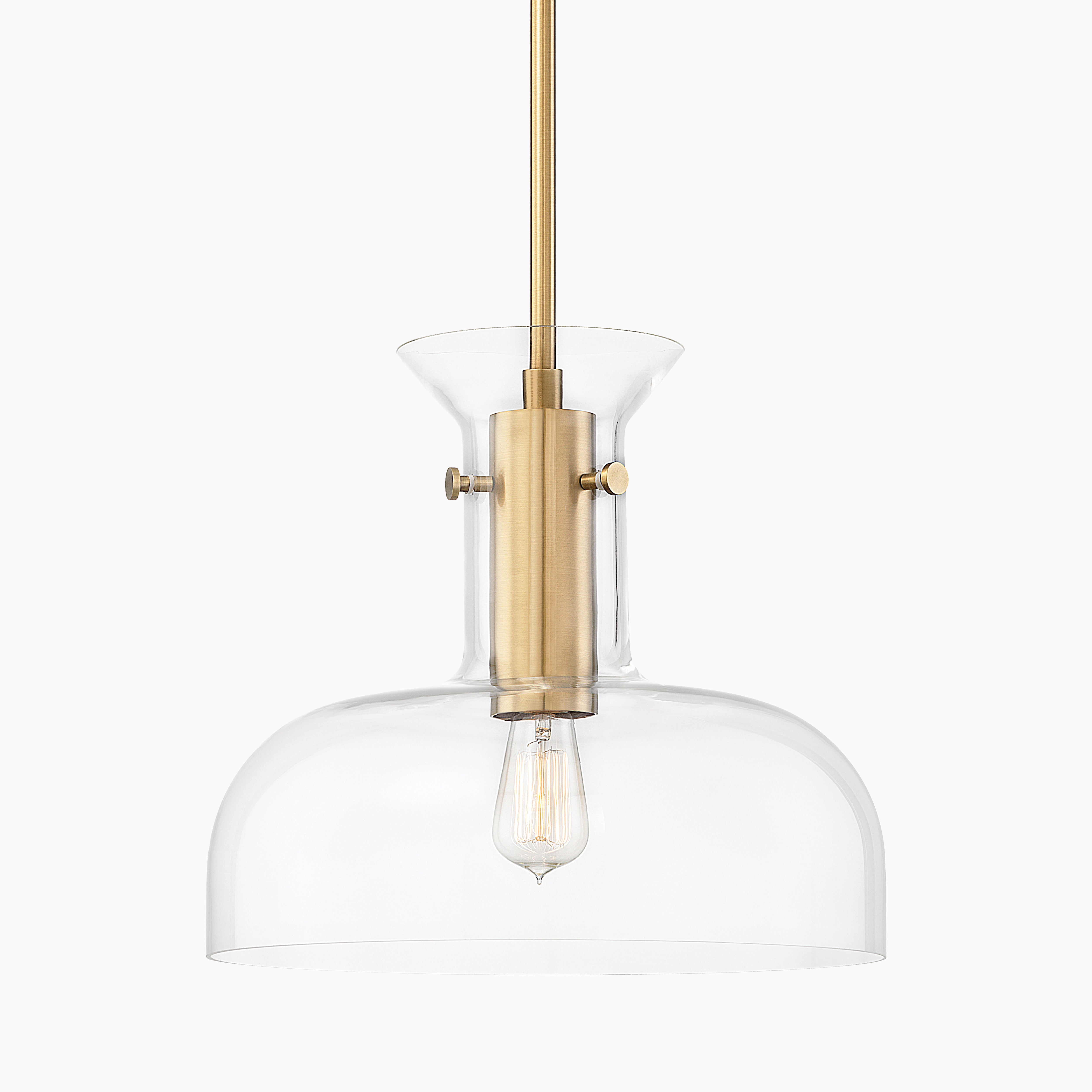 Pendant light in aged brass with a cylindrical metal fixture and clear glass shade, showcasing an exposed vintage-style bulb.