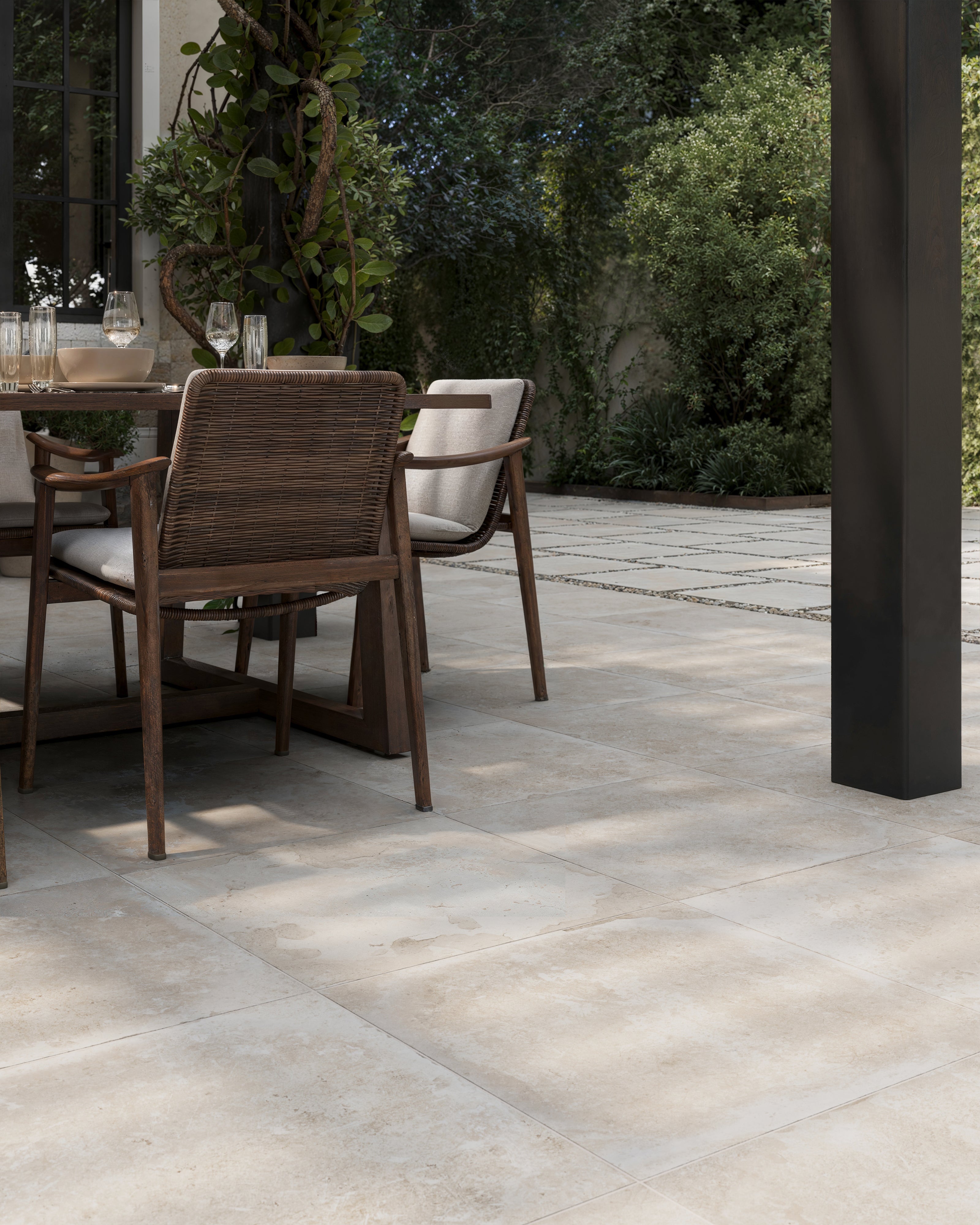 Elegant outdoor dining setup featuring Bowden 24x24 Grip Porcelain Pavers in Oat, creating a seamless and natural ambiance.