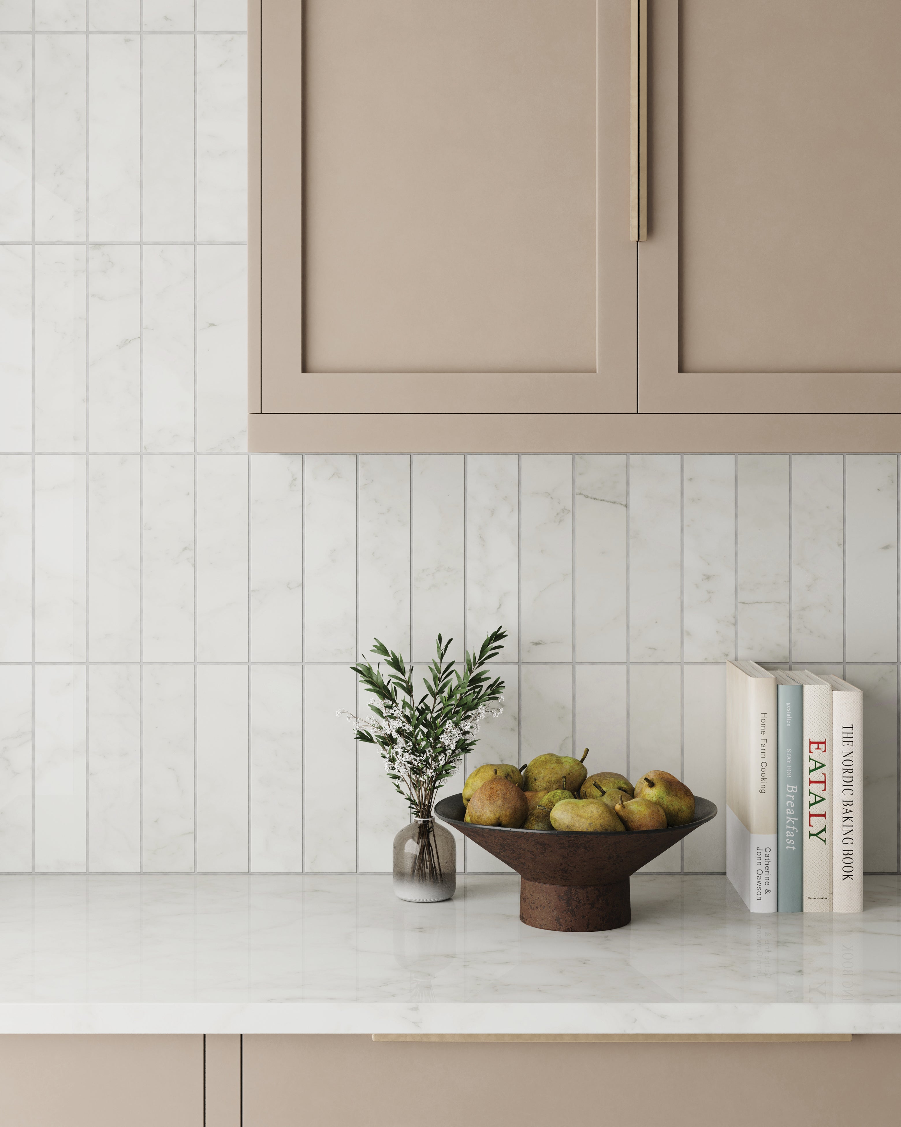 Chic kitchen design featuring polished Carrara marble look tiles, soft beige cabinetry, and a minimalist display of fresh pears and cookbooks.