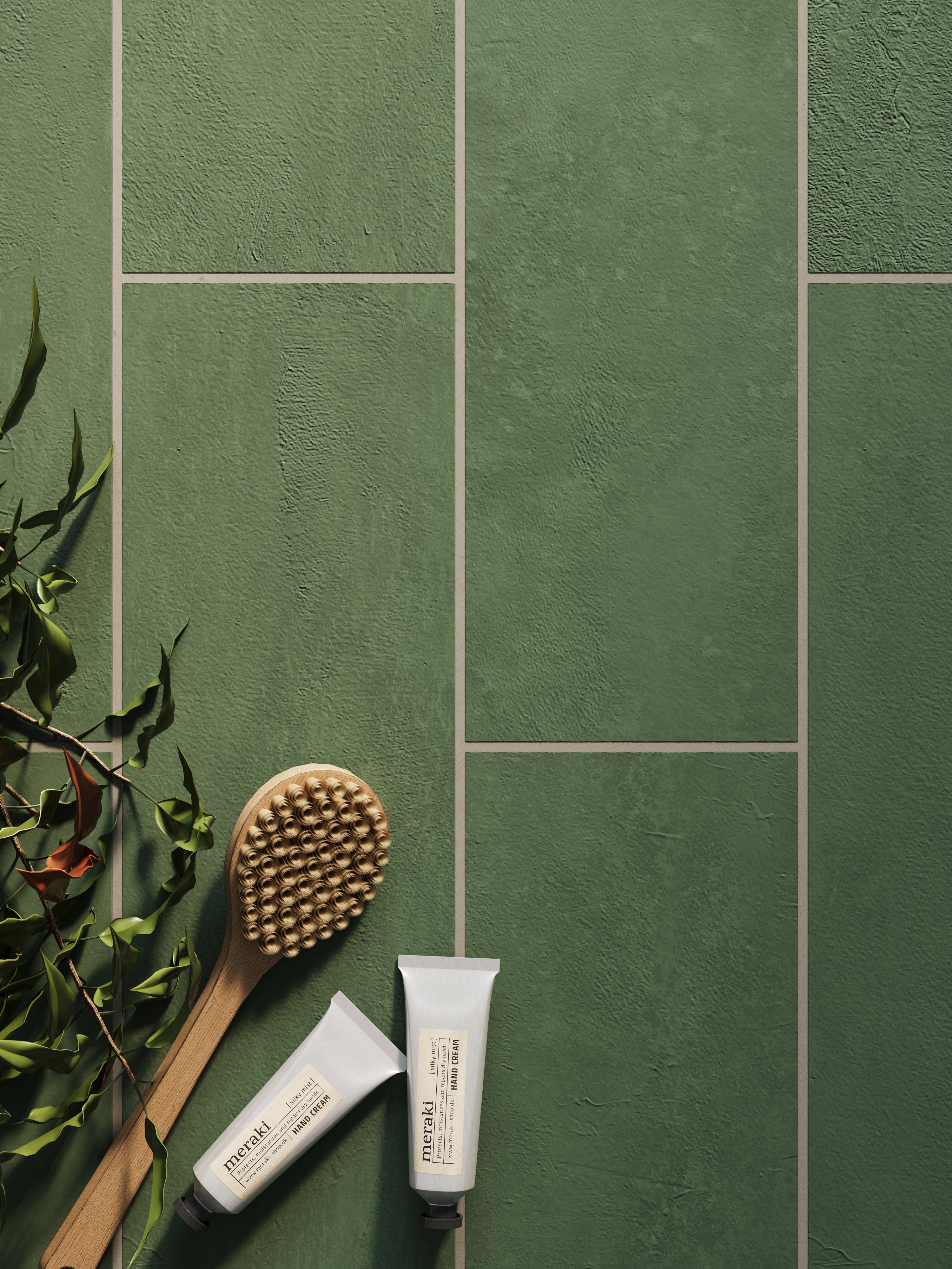 Dax Forest 6x24 matte porcelain tiles, featuring a deep green tone and textured surface, paired with natural bath essentials for a calming aesthetic.