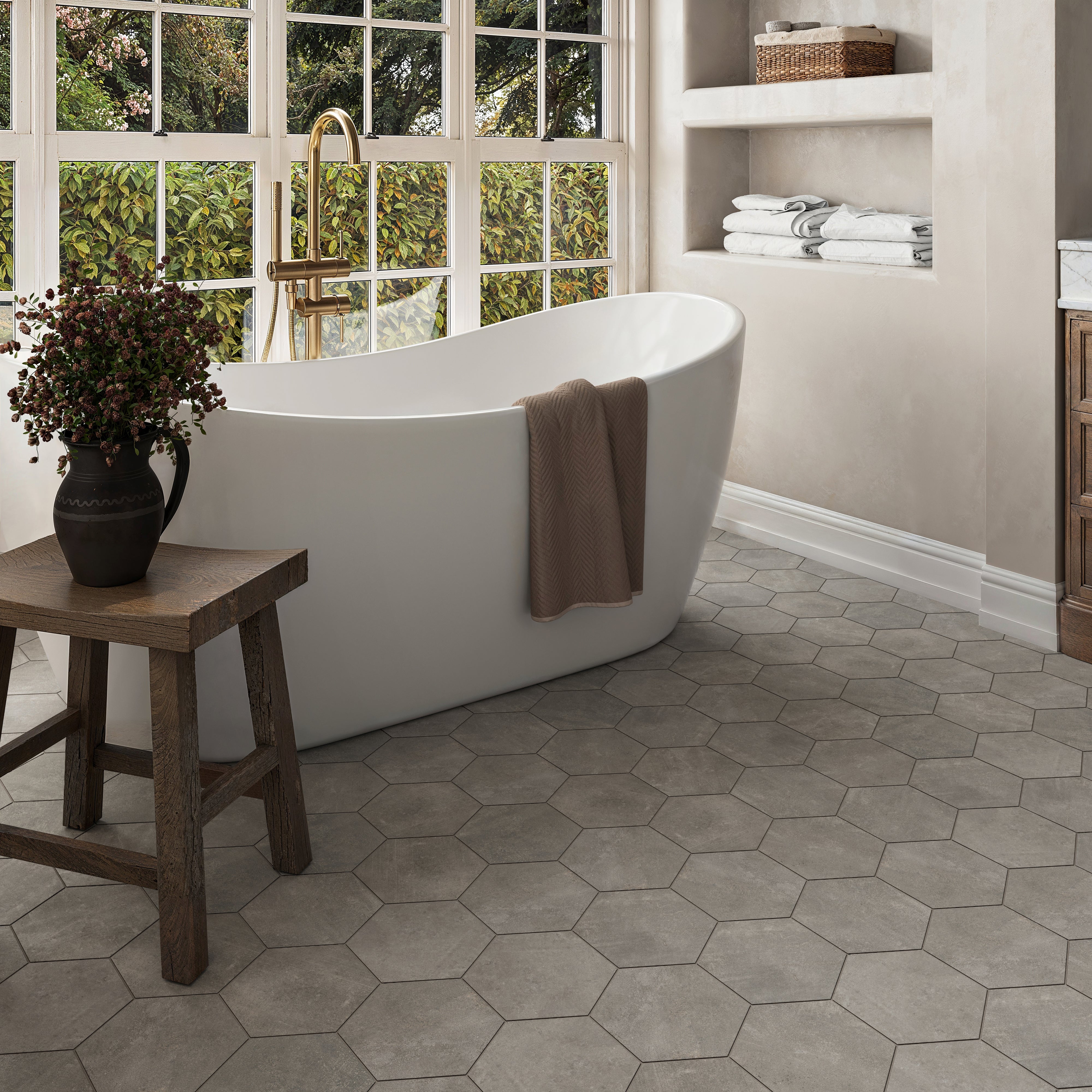 Elegant bathroom with dark grey hexagon tile flooring, a freestanding tub, and warm natural accents
