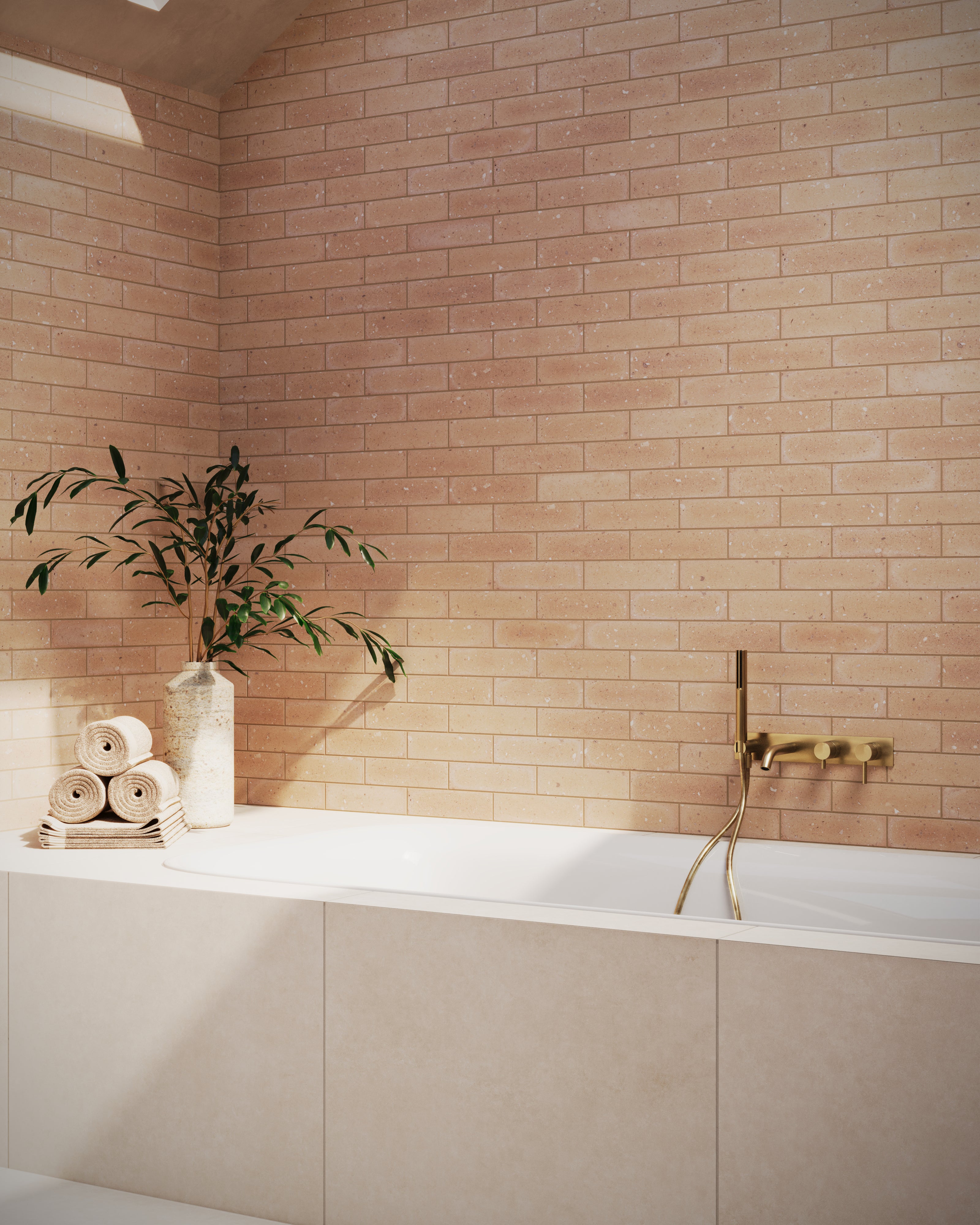 A serene bathroom showcasing a freestanding tub clad in Wyatt 32x32 matte porcelain tile in a dune beige tone, complemented by gold fixtures.