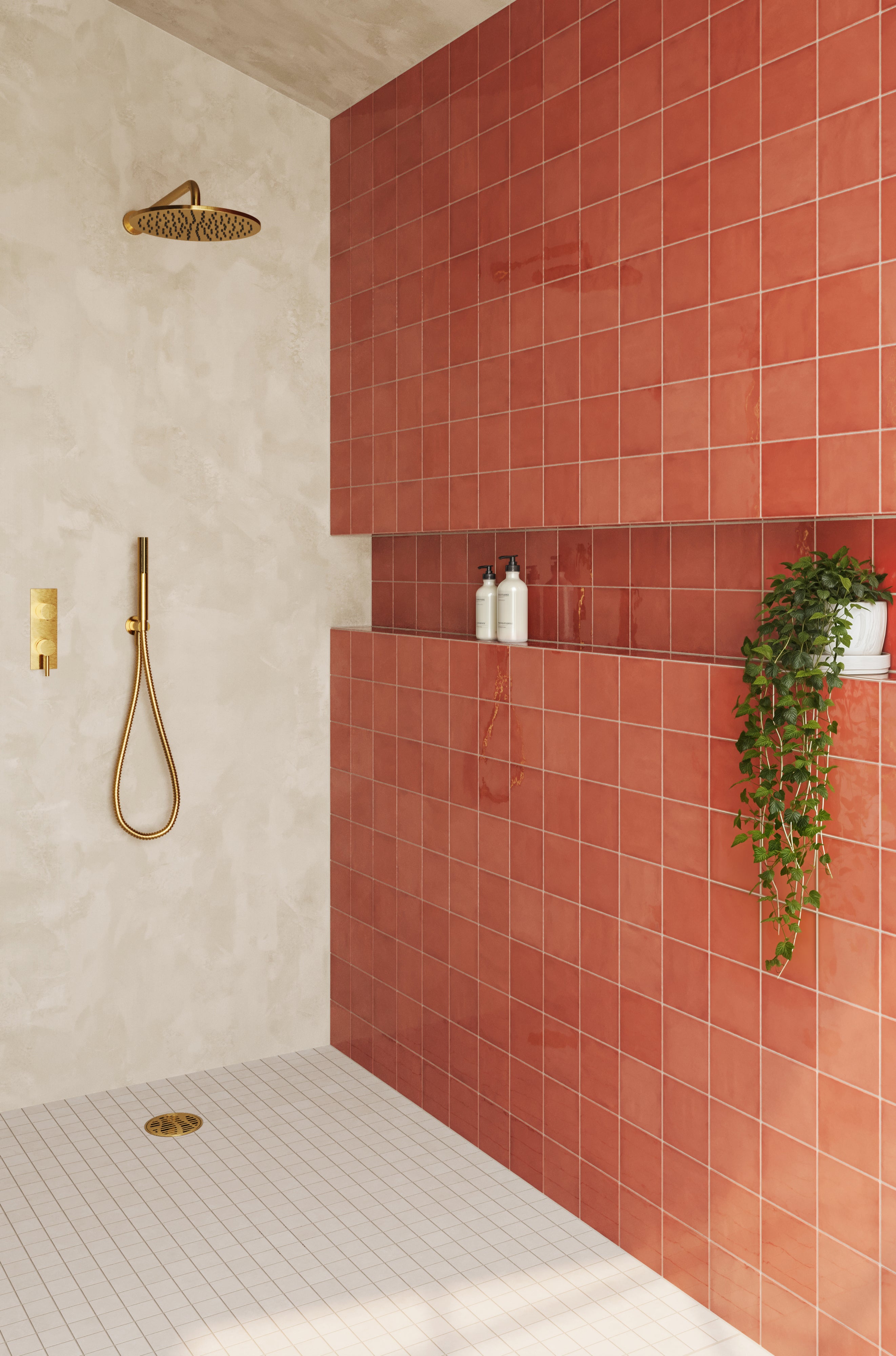 Bright and inviting shower space featuring vibrant red subway tiles paired with soft neutral walls, accented by gold fixtures and a cascading green plant.