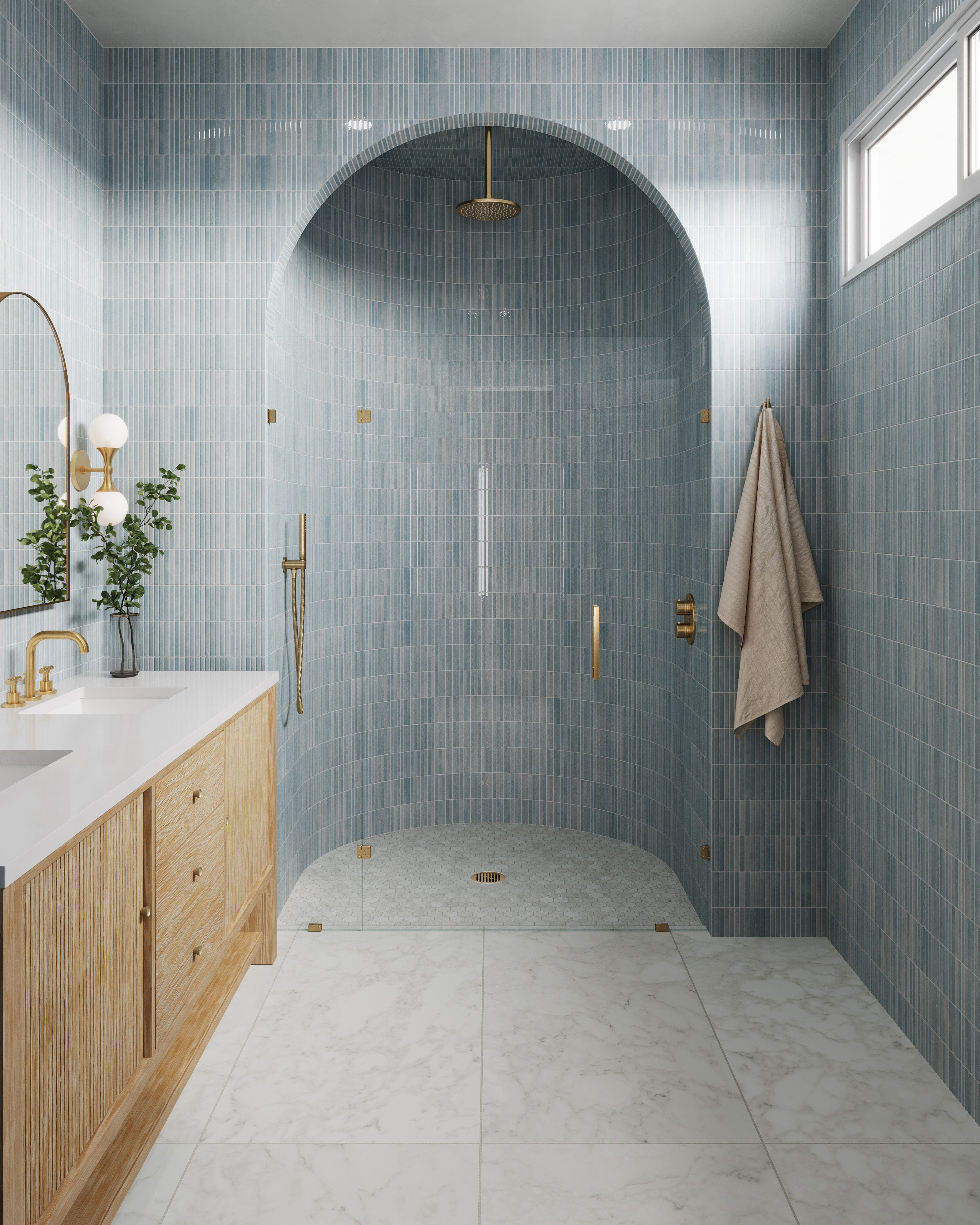 Arched walk-in shower clad in glossy ice blue vertical tiles, complemented by a sunwashed oak vanity, gold fixtures, and large white marble-look flooring