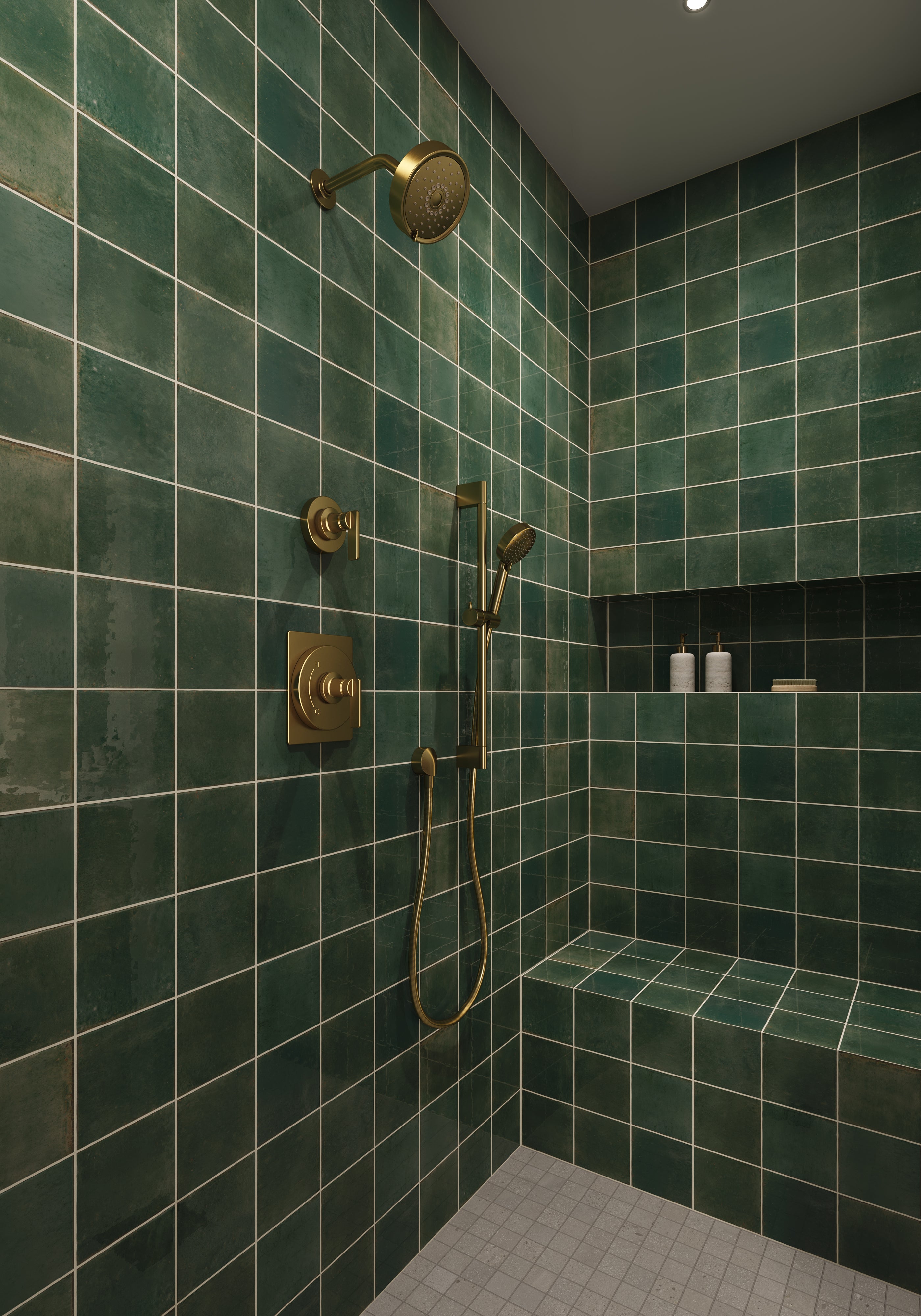 Bathroom shower lined with green porcelain tiles that show a weathered, rustic finish, highlighted by warm gold hardware.