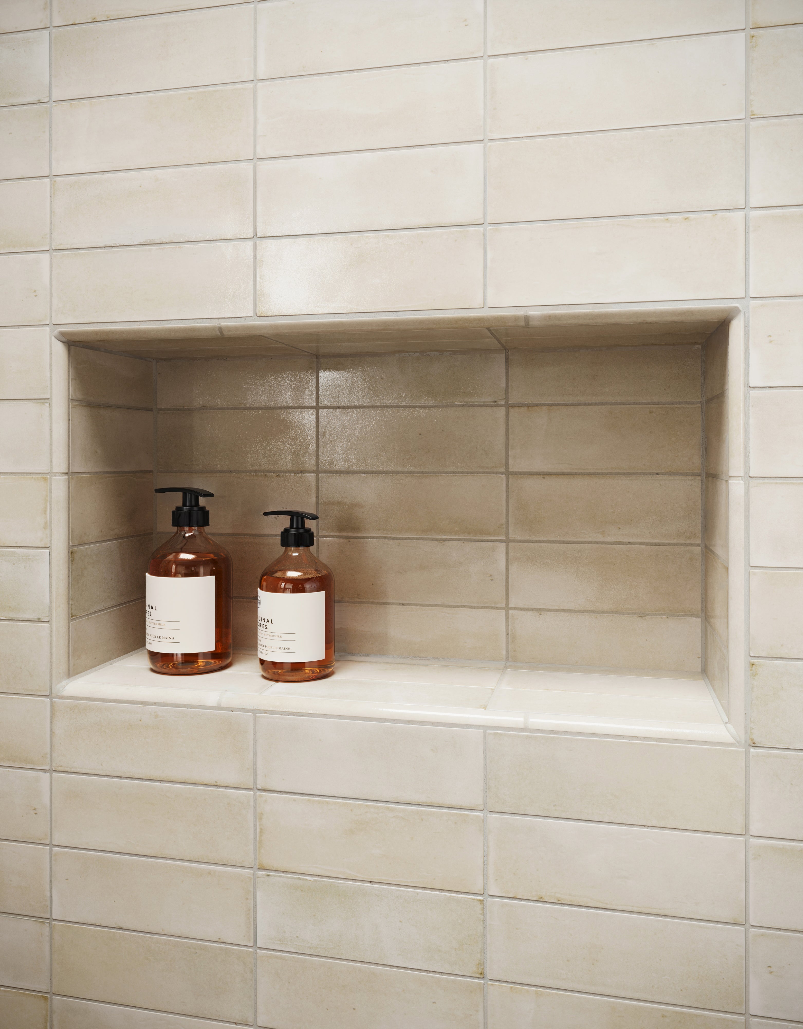 Glossy Natasha 0.5x8 ceramic trim in Bone beige color gracefully frames the recessed niche, providing seamless edge detailing with a polished finish.