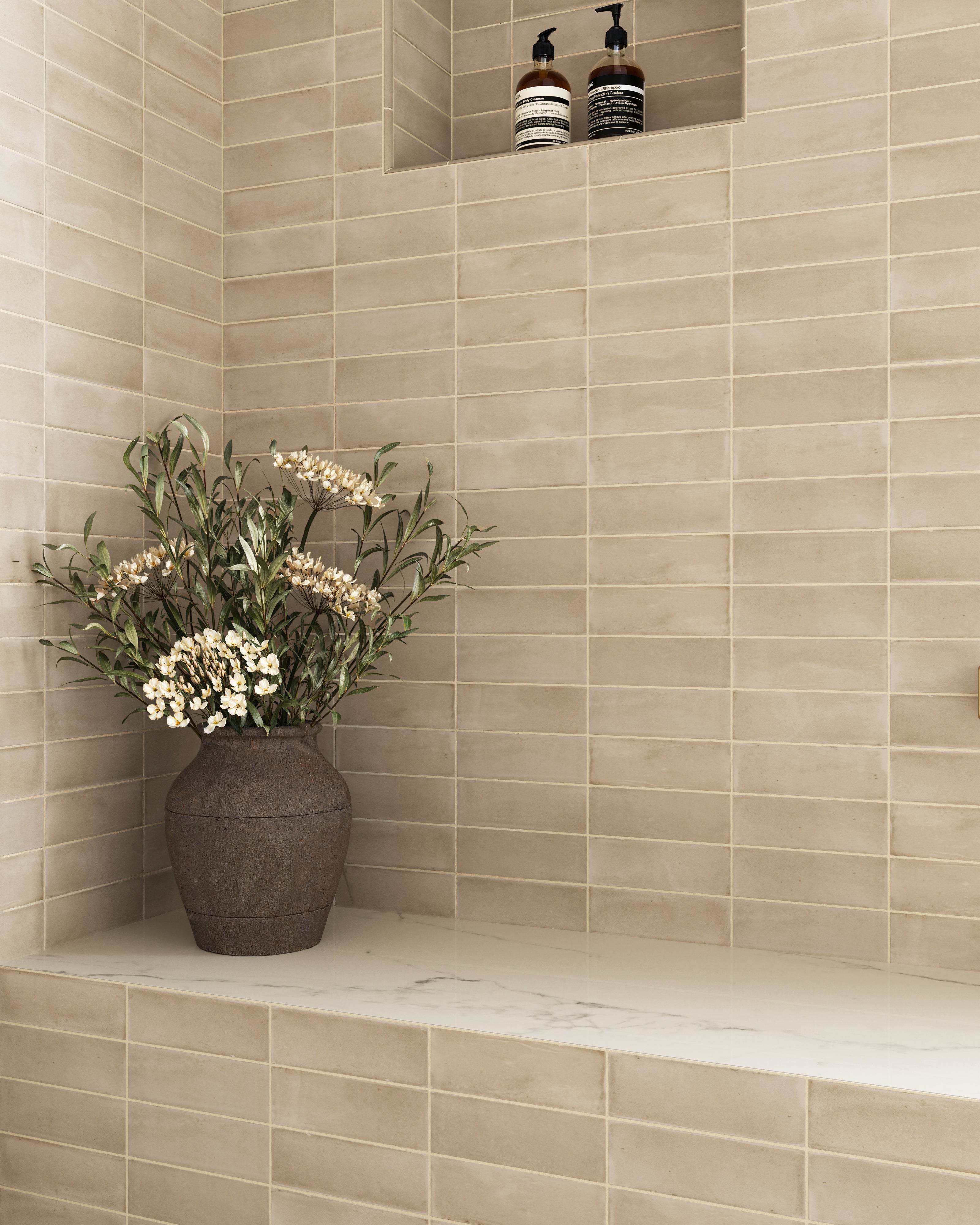 Close-up of Natasha 2x6 matte porcelain tile in Bone lining a shower bench nook, creating a soft beige canvas with timeless elegance.