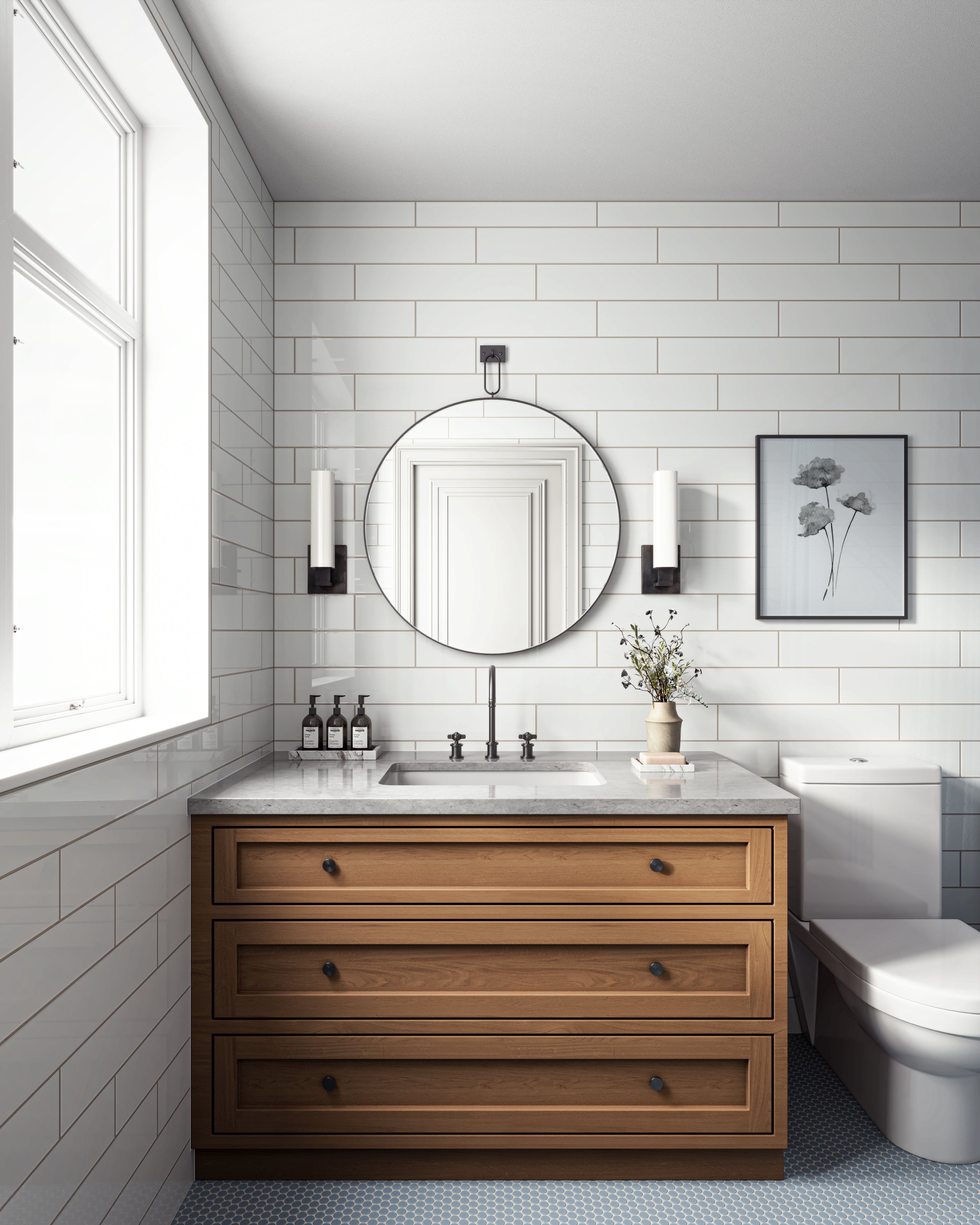 Modern bathroom with a round wall mirror, wood vanity with marble top, wall sconces, white subway tiles, and a toilet.