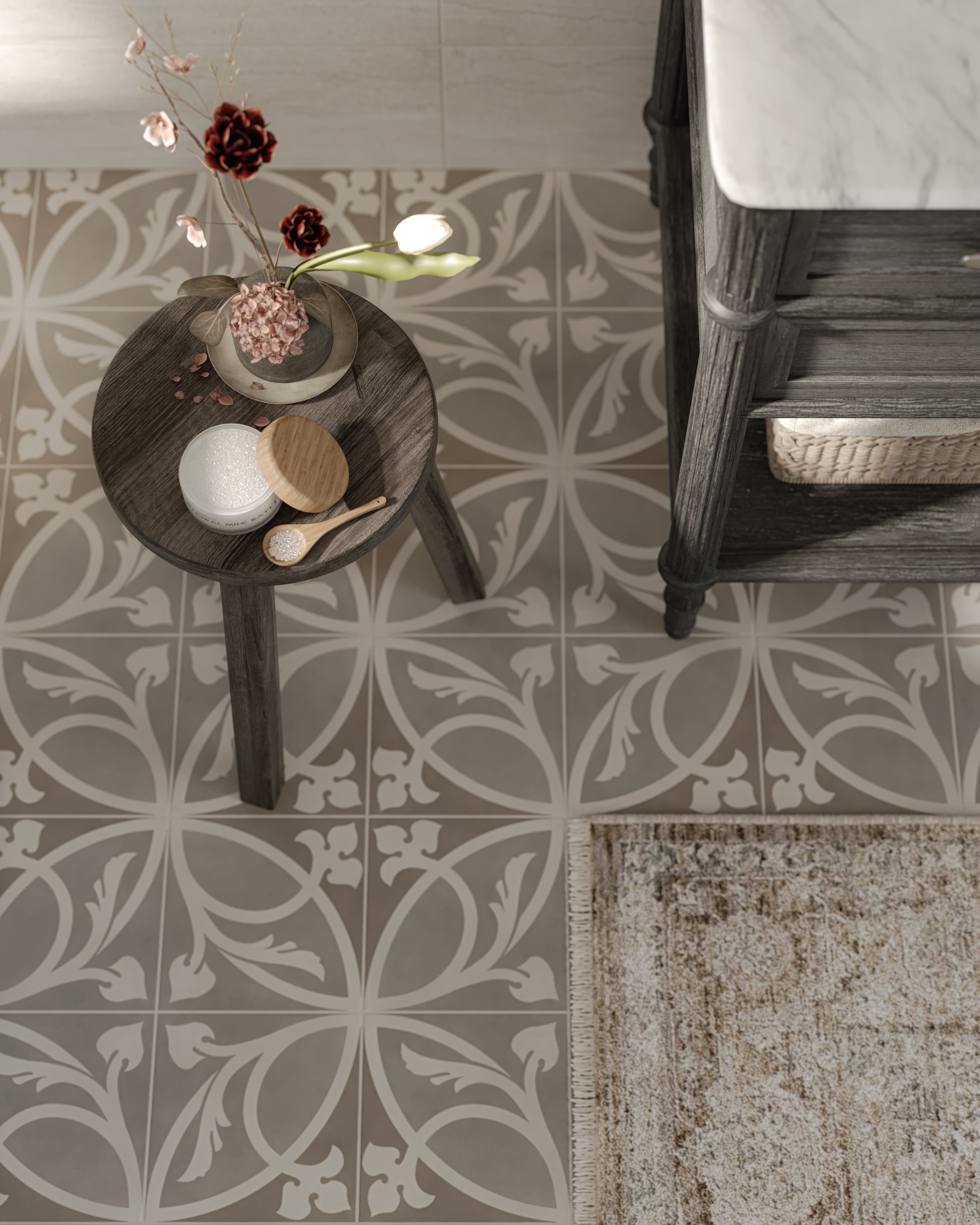 Overhead view of Brielle 8x8 patterned floor tiles with a rustic rug, dark wooden stool holding flowers, and a vanity with marble top.