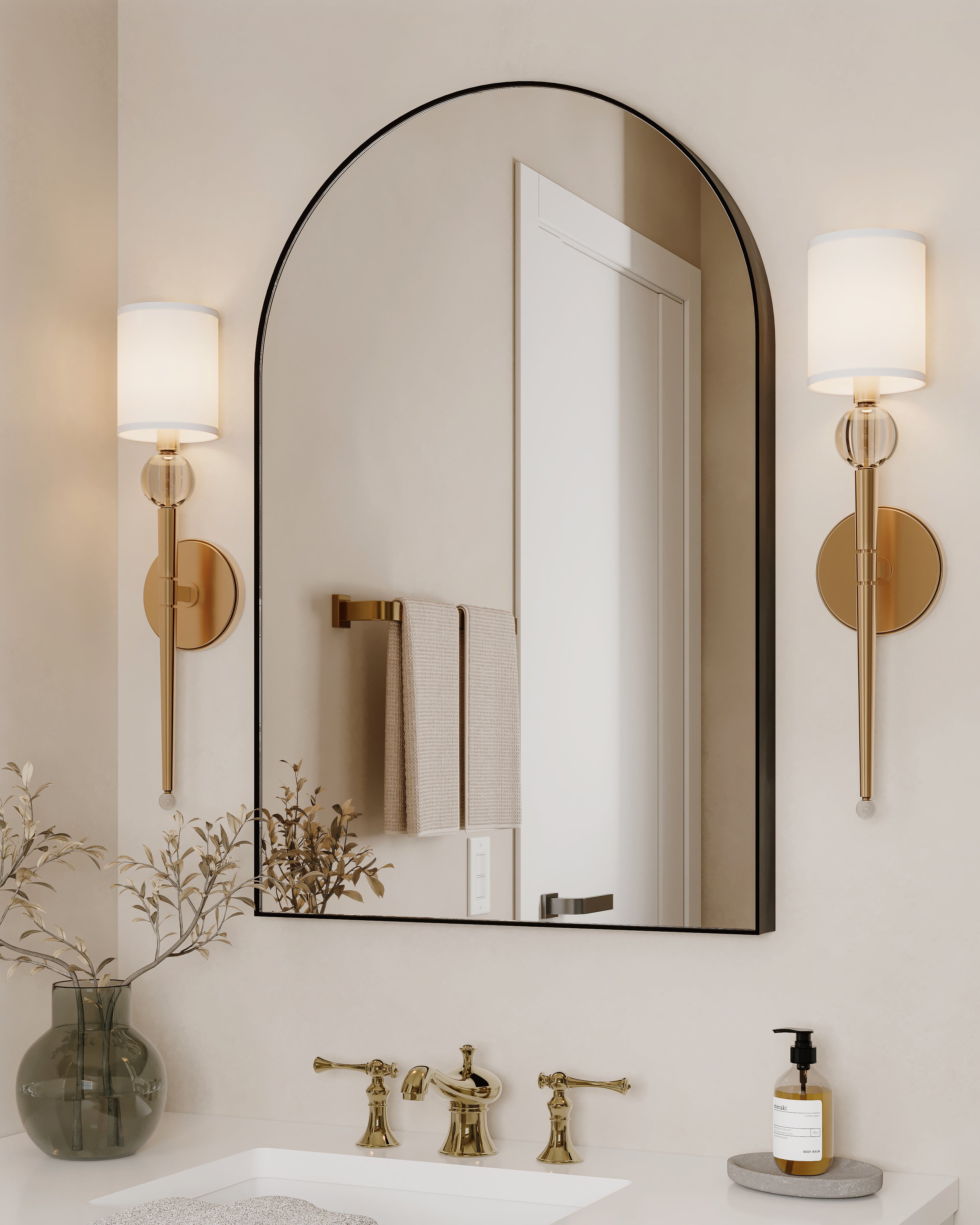 Arched matte black mirror in a modern bathroom, flanked by gold sconces and paired with brass fixtures for a timeless, elegant look