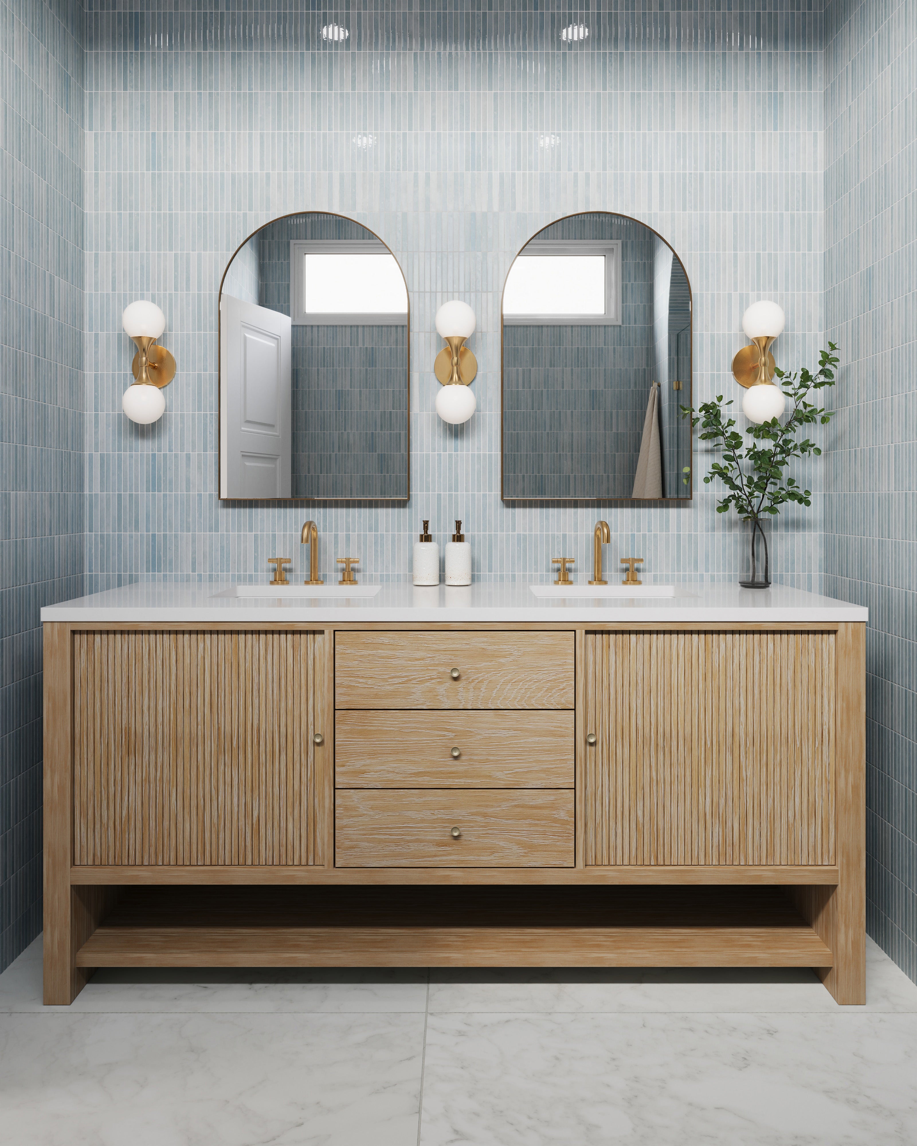 Sunwashed oak double vanity with fluted doors, brass fixtures, and arched mirrors on sky-blue tile walls.