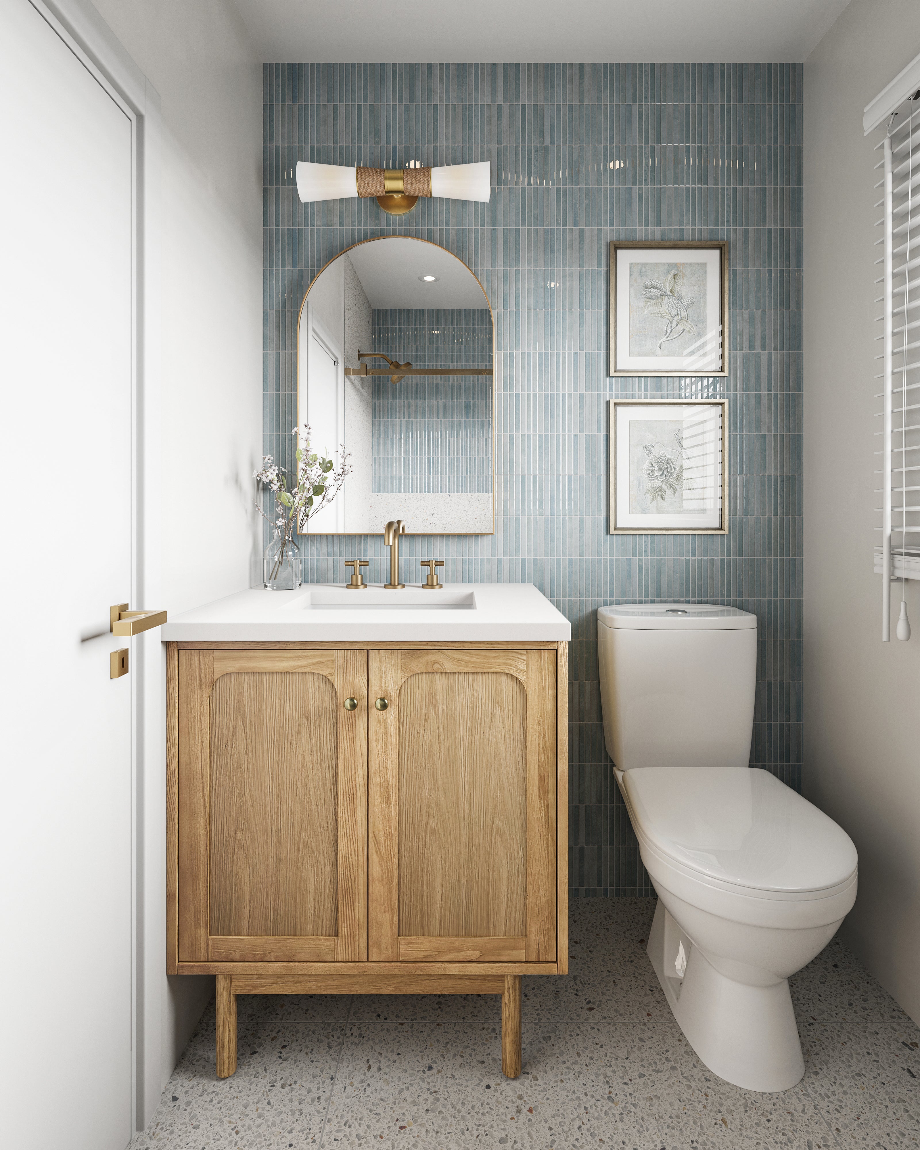 Charming powder room with vertical ice-blue tiled wall, arched brass mirror and sconce, and compact oak vanity with integrated white quartz countertop.