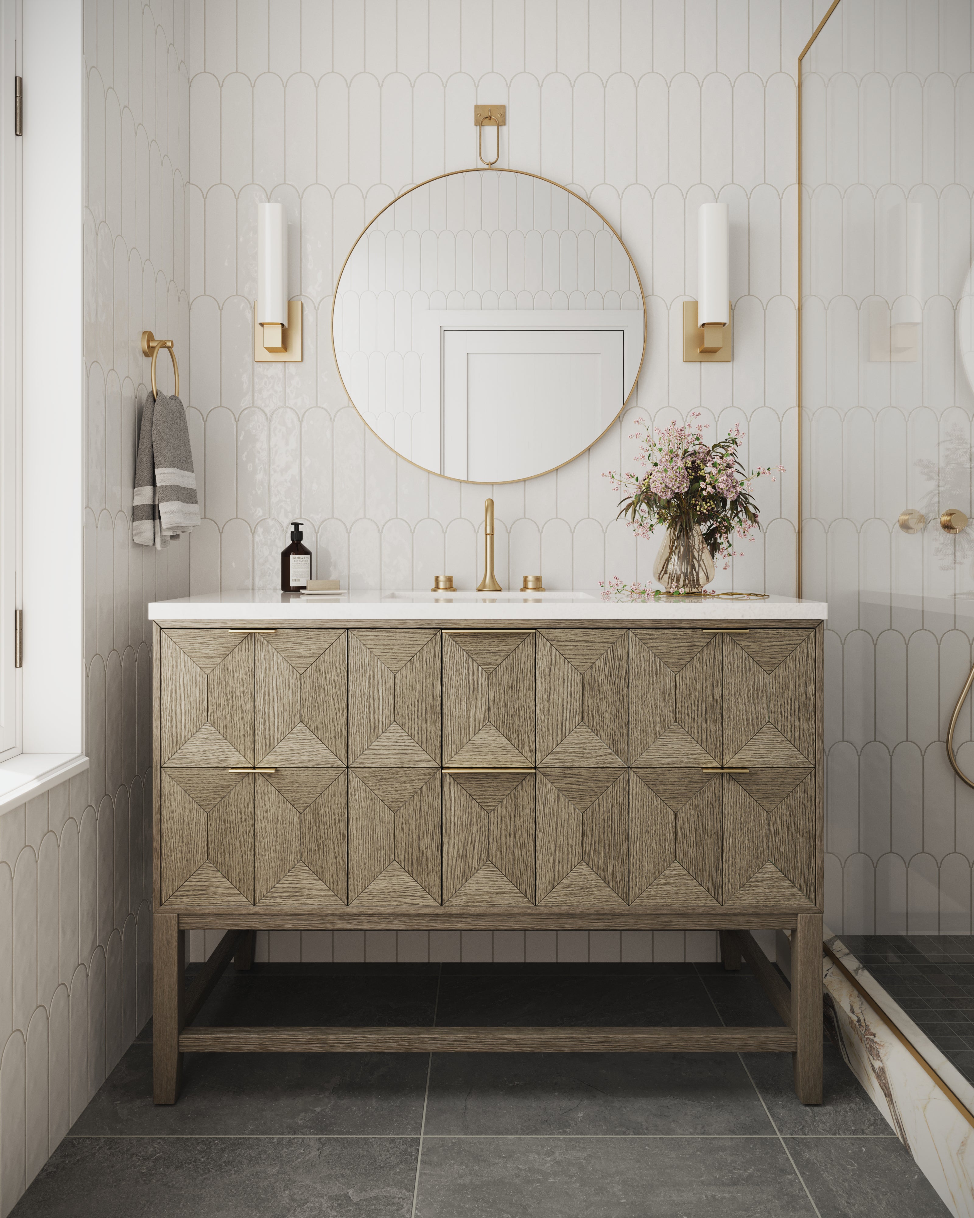 Elegant Gwen 48" vanity in pebble oak with diamond-patterned drawers and brass hardware styled with a large round mirror, set against white fish scale wall tiles.