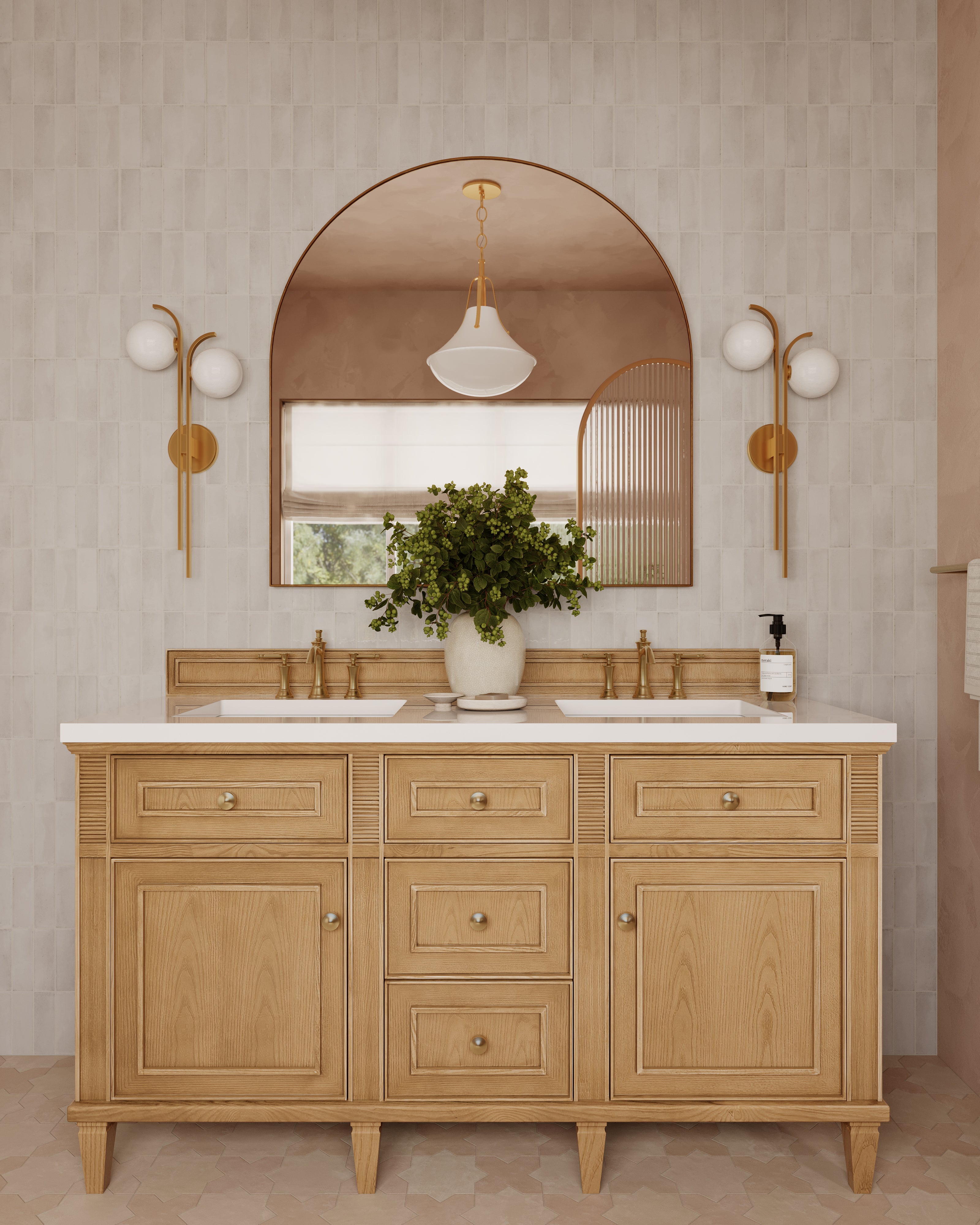 Bathroom with a natural oak double vanity, arched mirror, and two aged brass wall sconces with frosted glass globes on tiled walls.
