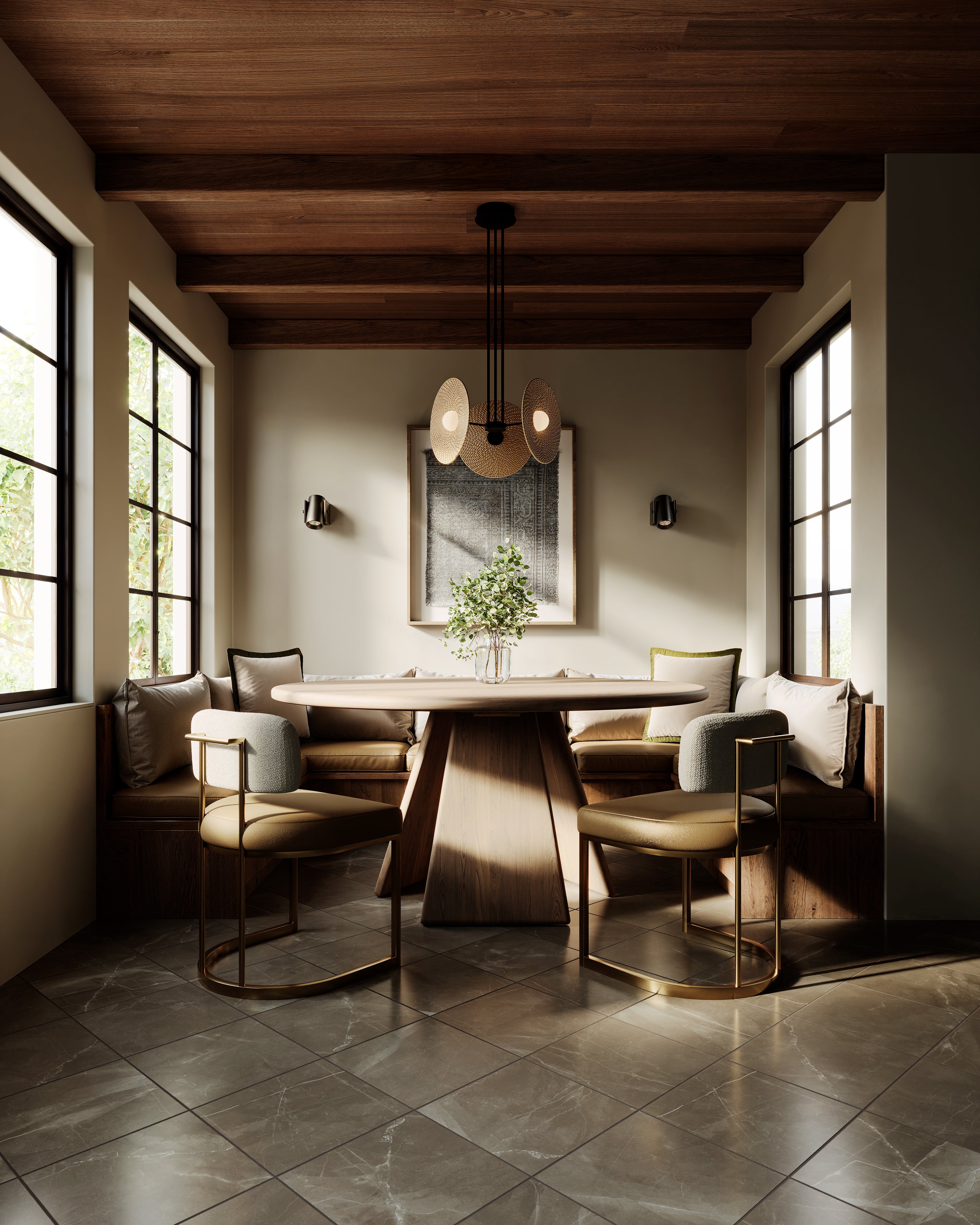 Warm, modern dining nook featuring a round solid wood pedestal table centered between built-in banquette seating, accented by brass-framed chairs, a sculptural pendant light, wood-beam ceiling, and soft natural light from tall windows.