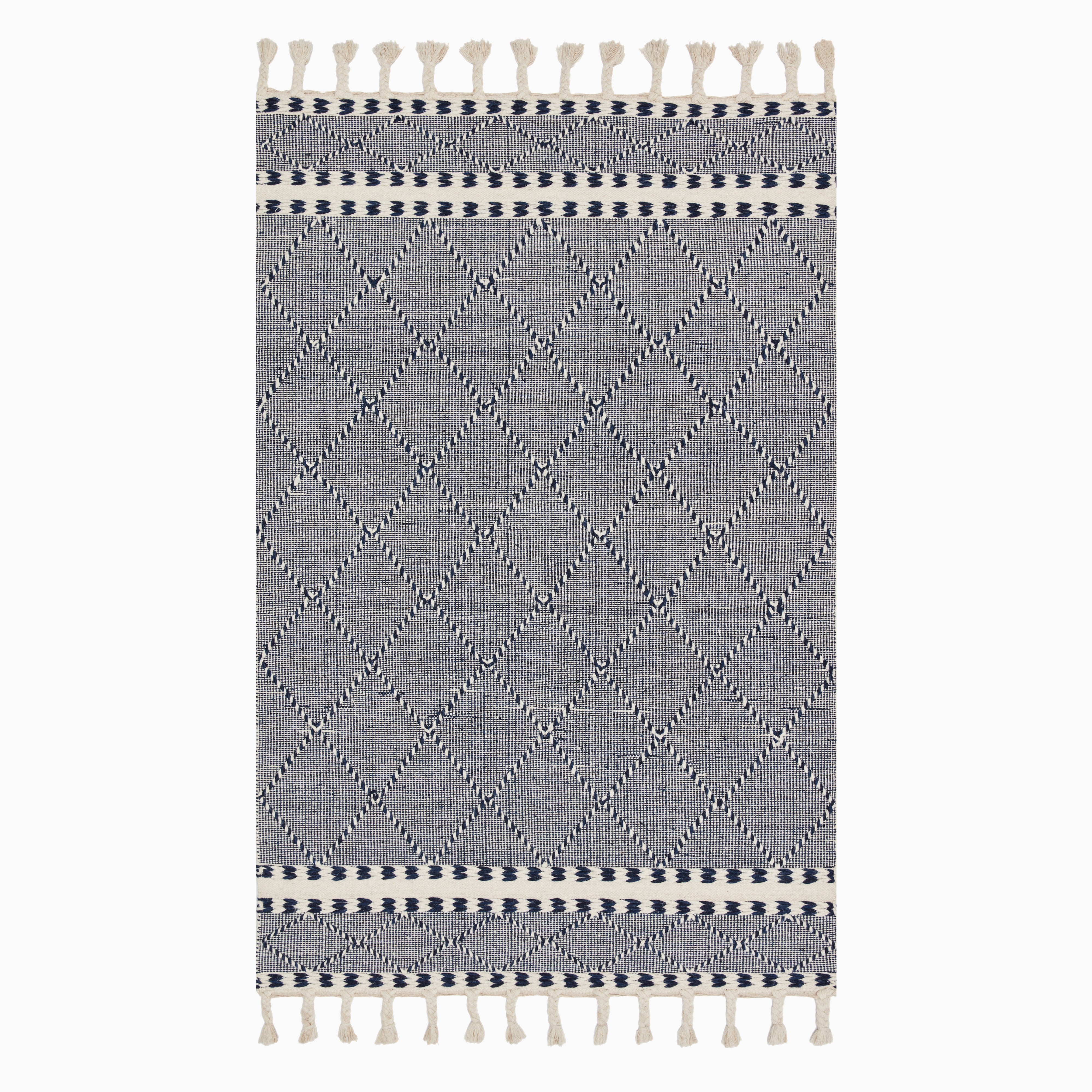Boho-inspired hand loomed wool area rug with a navy and white geometric diamond pattern and tassel fringe, blending style and texture.