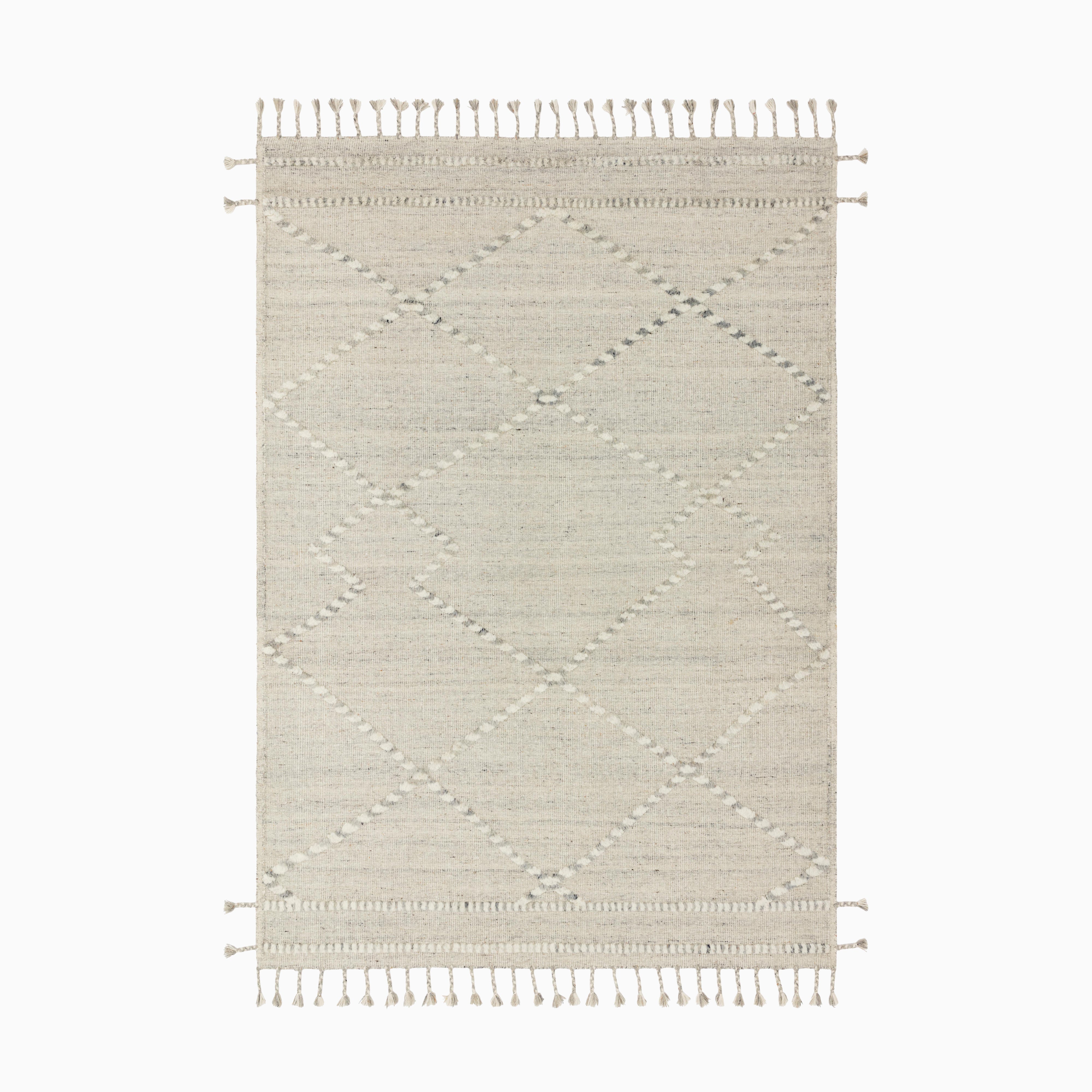 Hand-knotted rug crafted from a blend of wool, cotton, polyester, and rayon in cream and dove, featuring a subtle geometric pattern and tasseled edges for a contemporary finish.