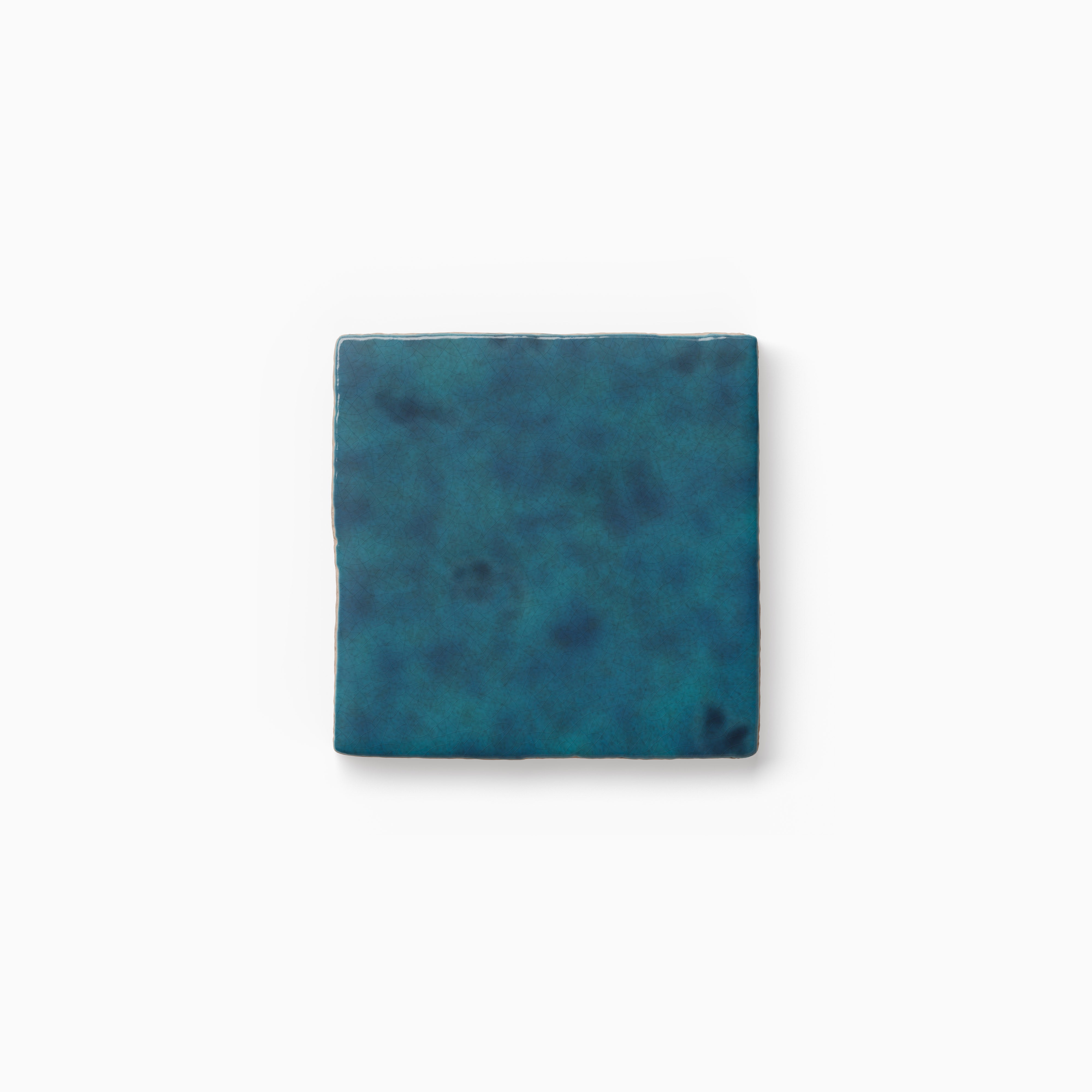 Deep blue tile sample with rich tonal variation, a softly mottled surface, and gently irregular edges displayed against a white background.