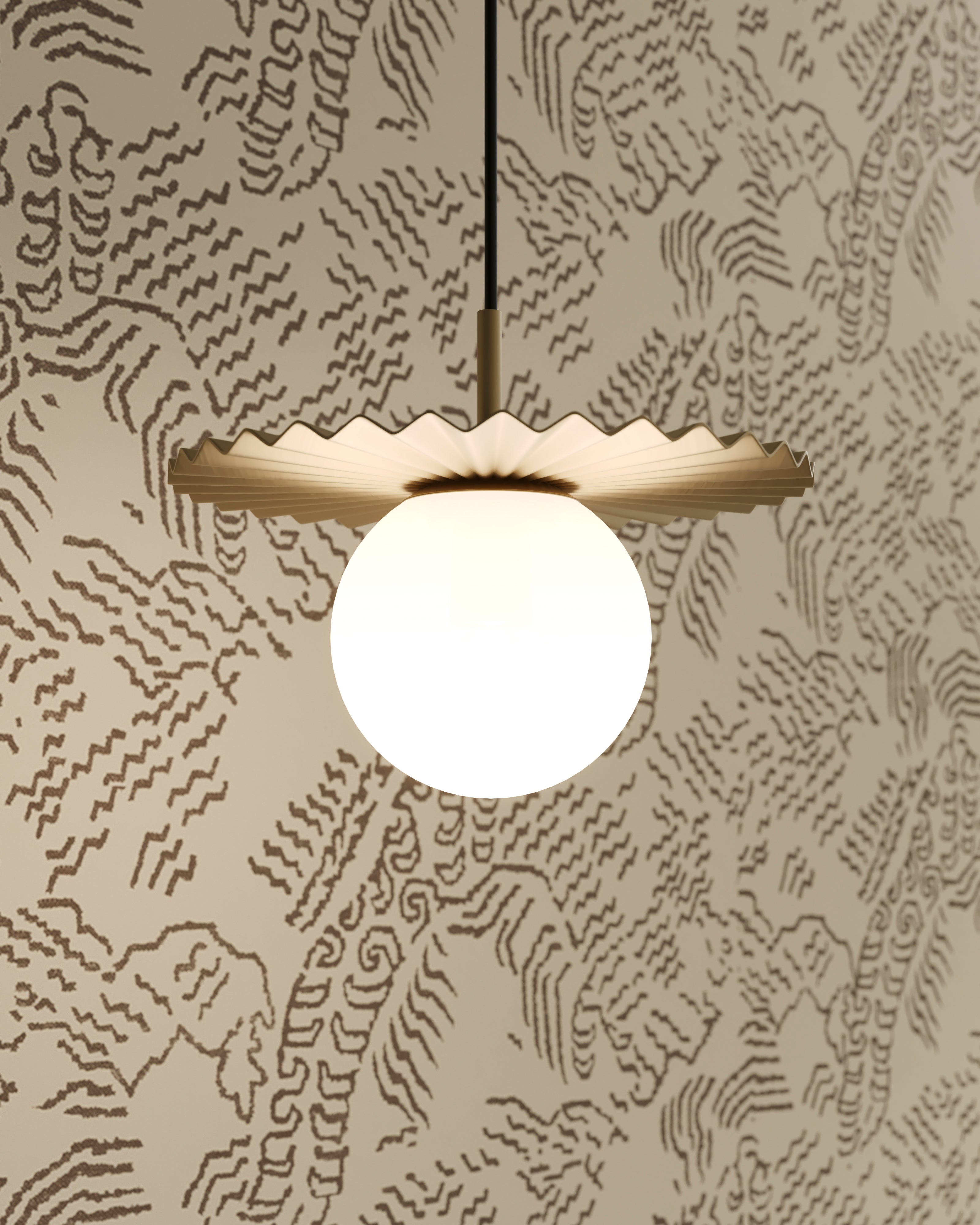 Brushed gold pendant with a pleated metal shade and glowing globe light set against patterned wallpaper.
